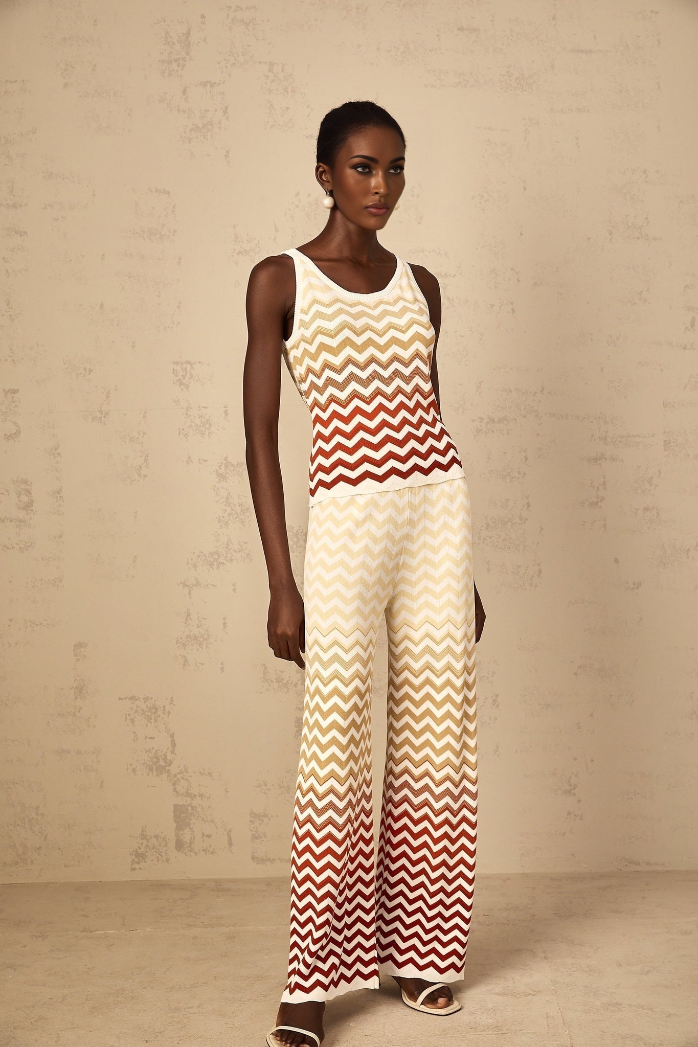 A woman wearing a yellow knit matching set with a zigzag pattern consisting of a long sleeve top and fitted pants