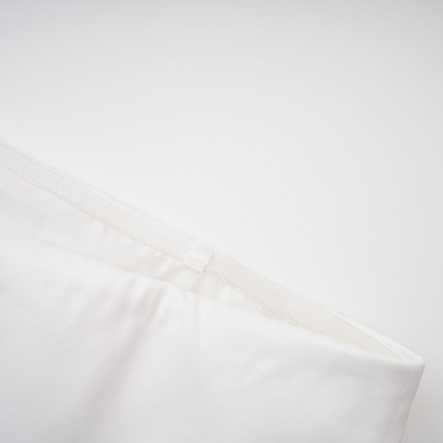 A woman wearing an elegant white off the shoulder dress with a flowing silhouette standing against a neutral background