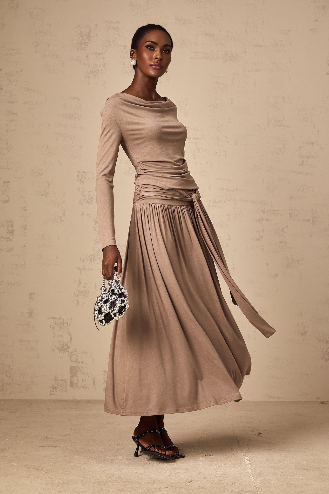 A woman wearing an oatmeal colored matching set consisting of a draped top and skirt both made from stretchy fabric