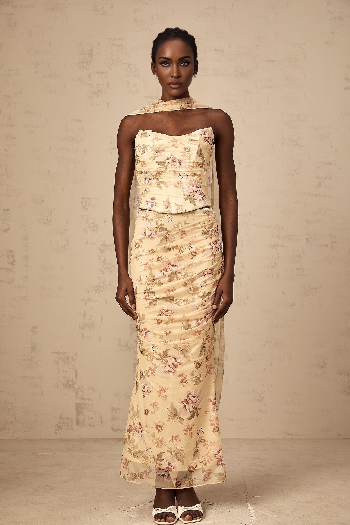 A yellow floral print matching set consisting of a fitted top and skirt worn by a model against a plain background