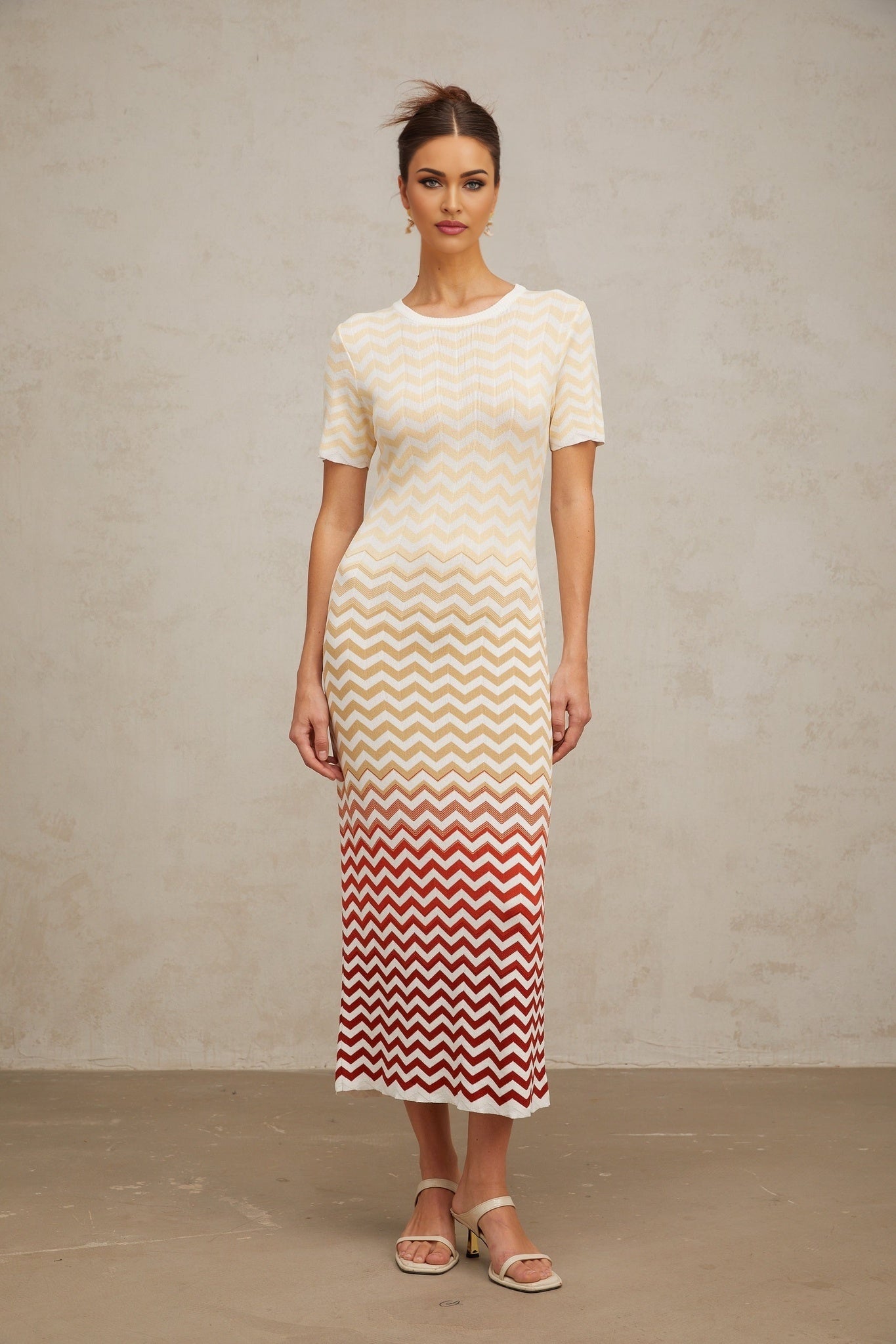 A yellow midi dress with a zigzag knit pattern worn by a model standing against a plain background
