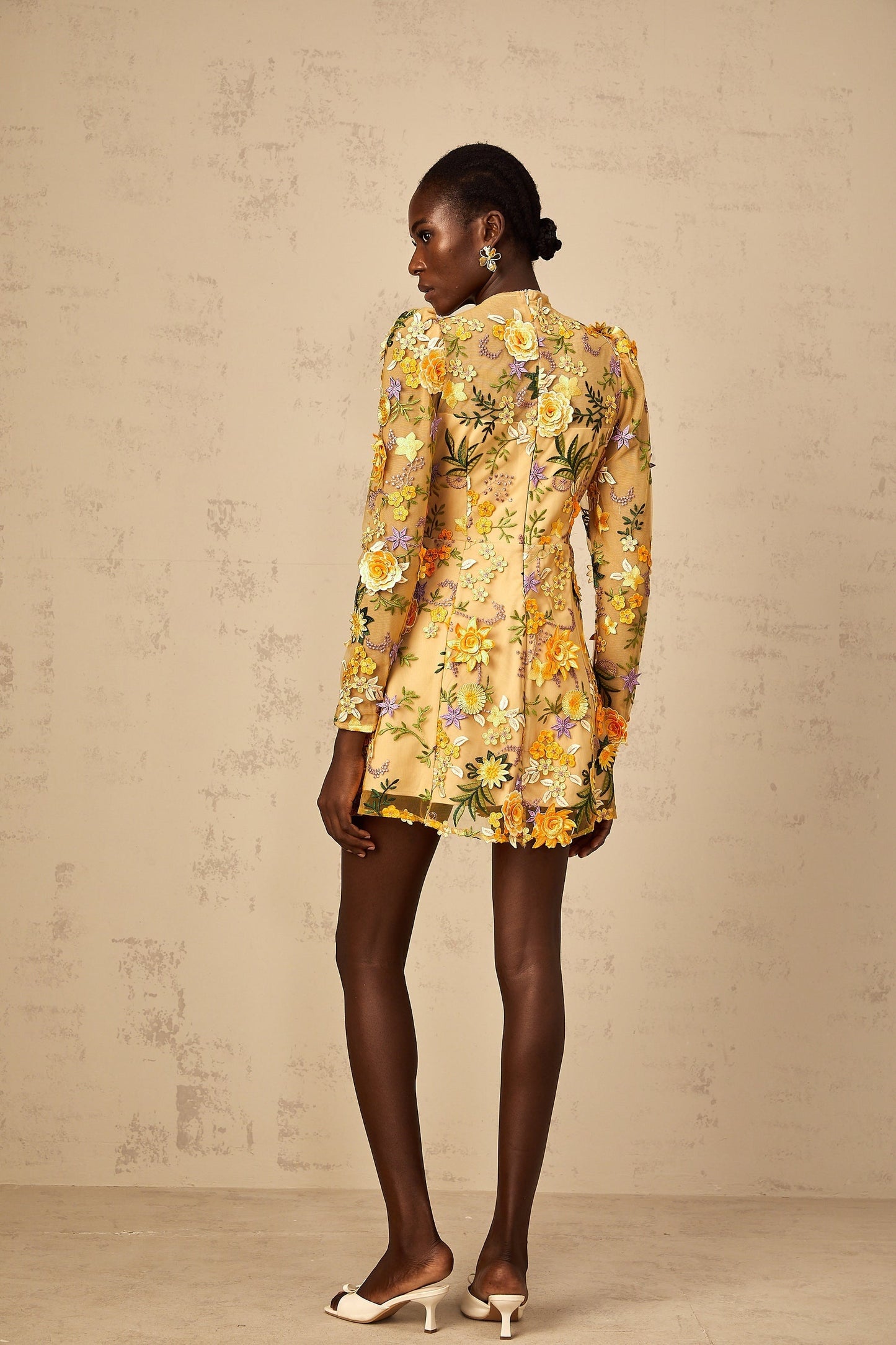 A yellow mini dress with 3D floral applique details named Jolien featuring a short hemline and decorative flower embellishments on the fabric