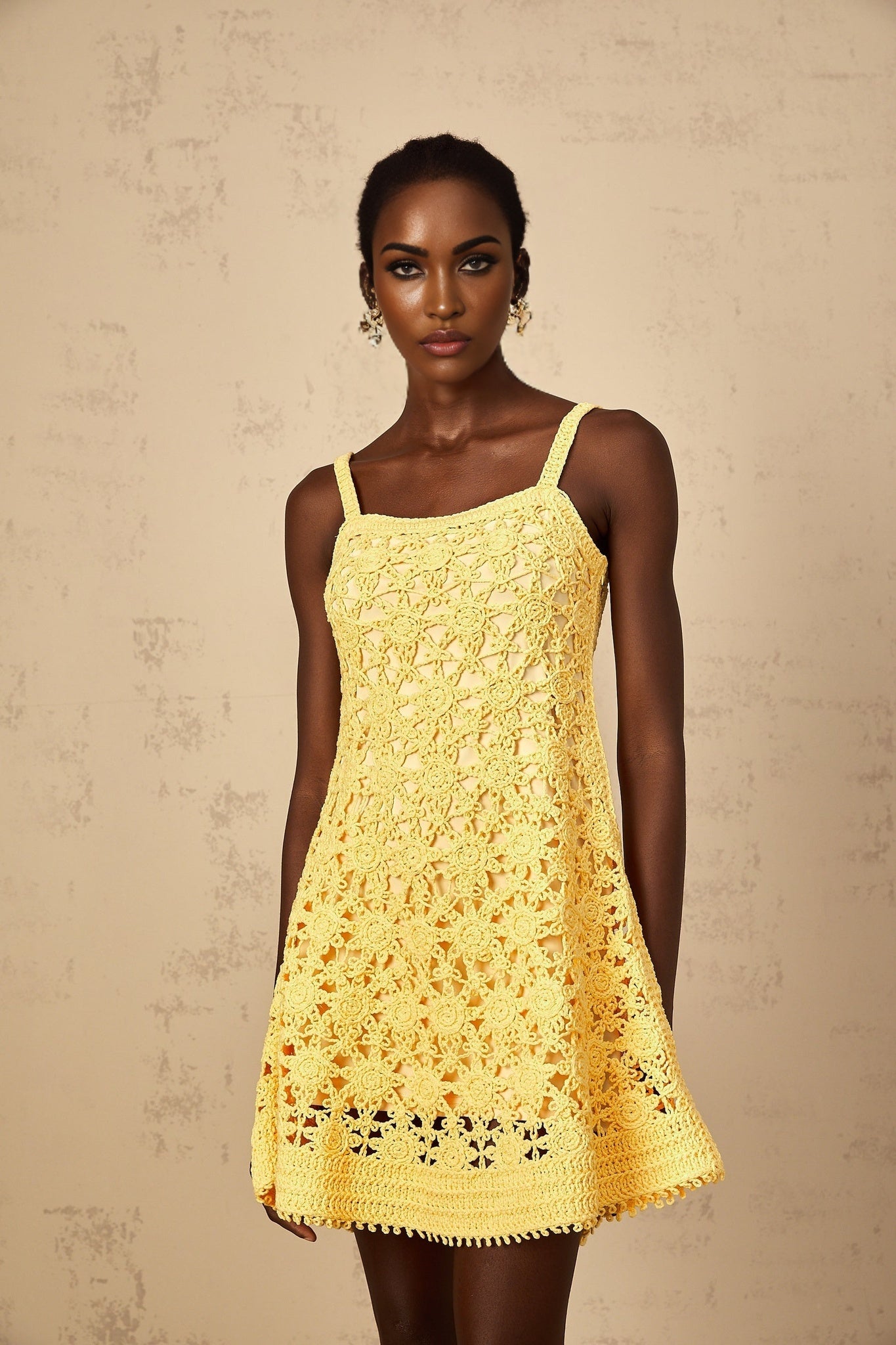 A yellow mini dress with a flared skirt and crochet knit pattern worn by a woman
