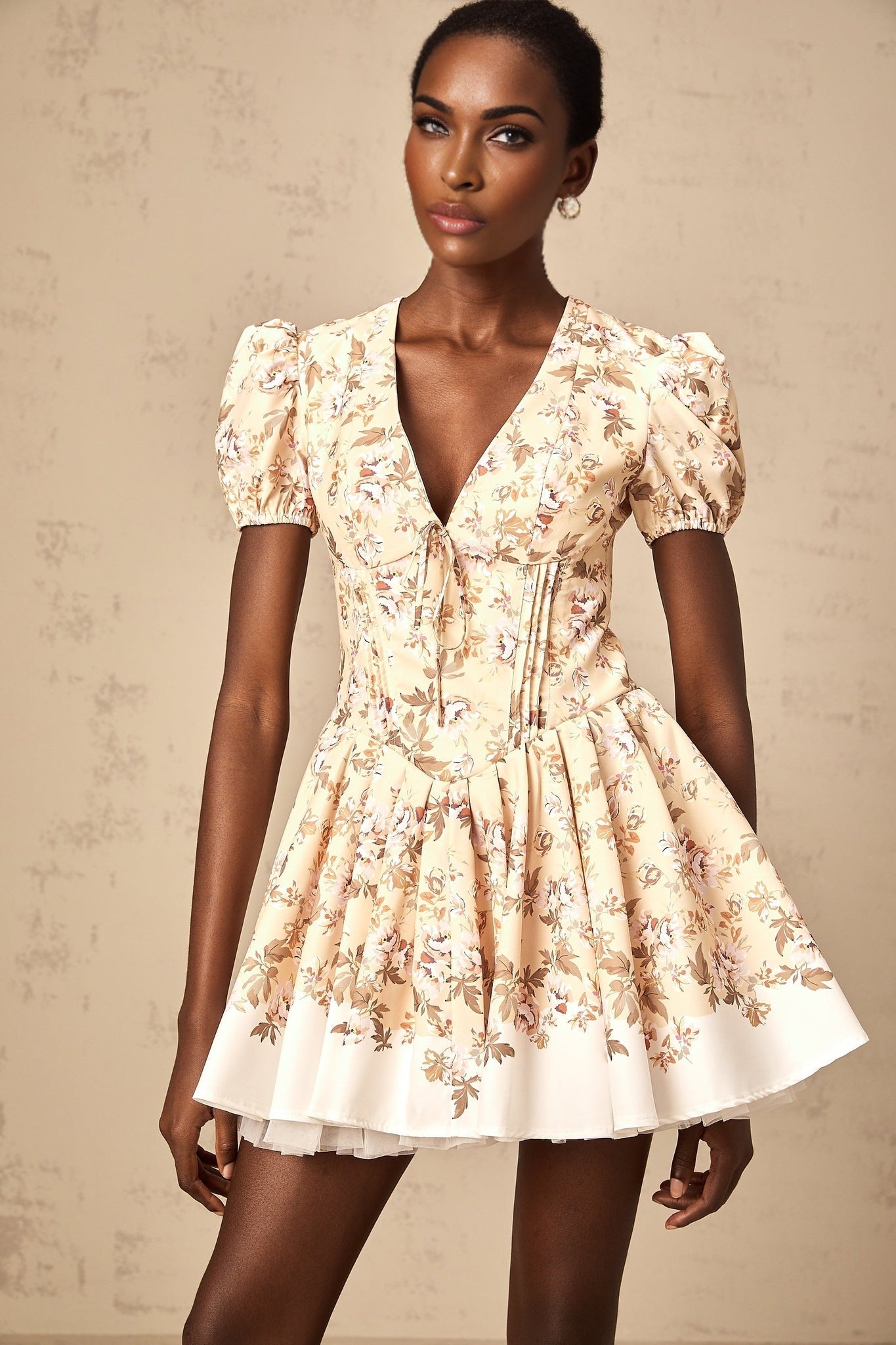 A yellow mini dress with a floral print pattern and pleated design featuring a short hemline and likely sleeveless or short sleeve style