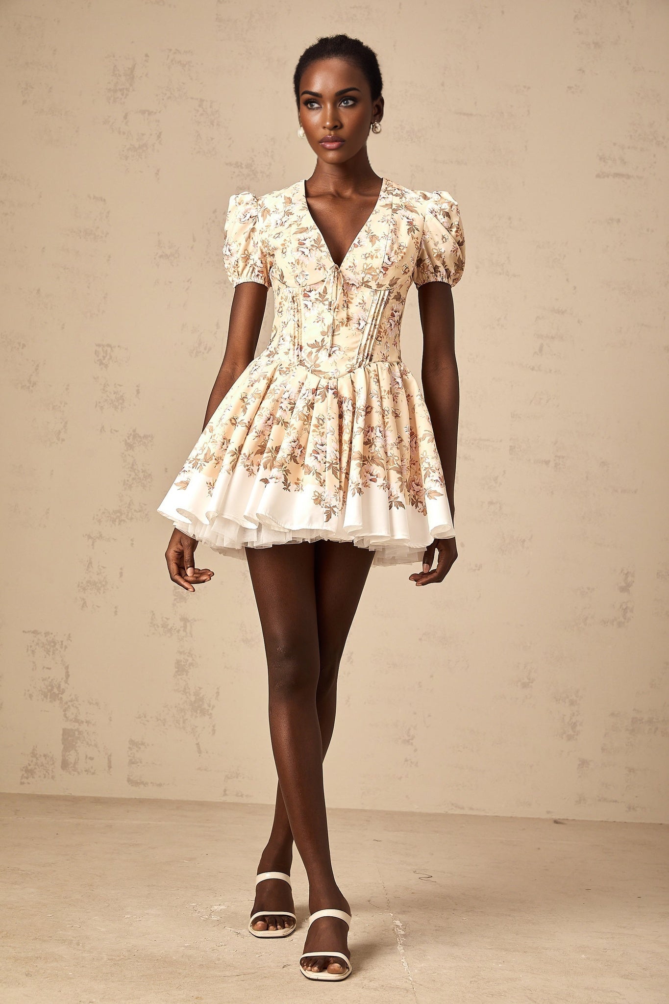 A yellow mini dress with a floral print pattern and pleated design featuring short sleeves and a flowy silhouette
