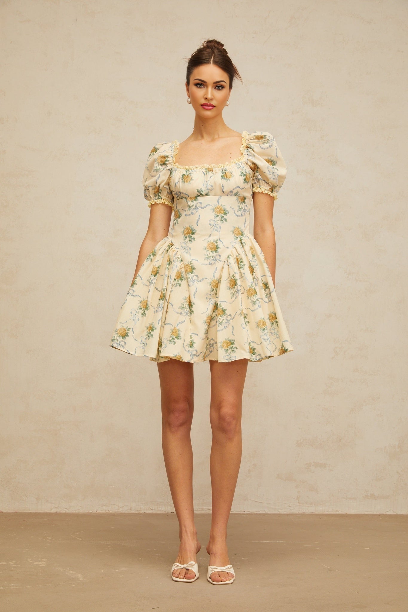 A yellow mini dress with a floral print pattern and shirred detailing named Tiphaine