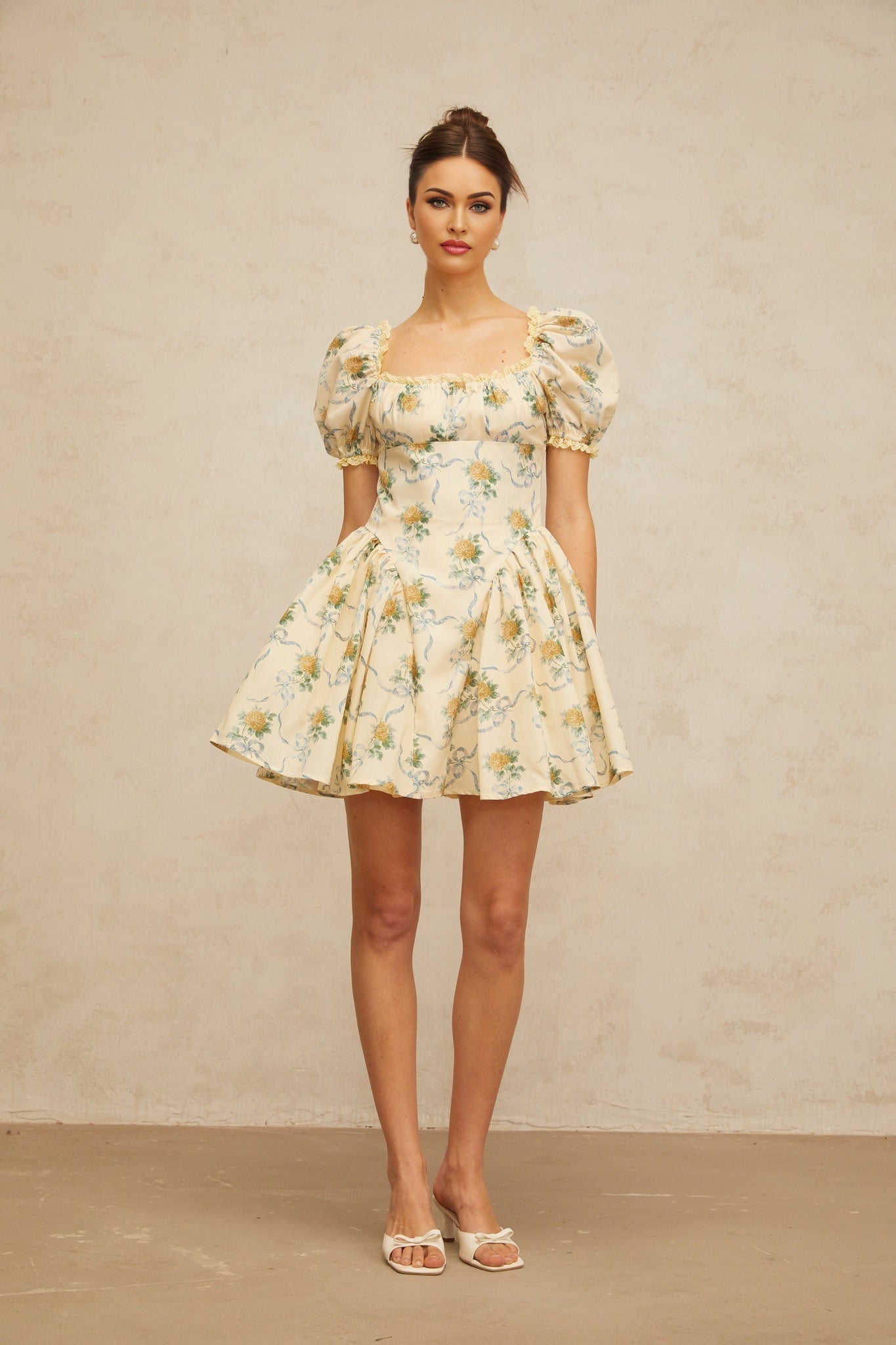 A yellow mini dress with a floral print pattern and shirred detailing named Tiphaine