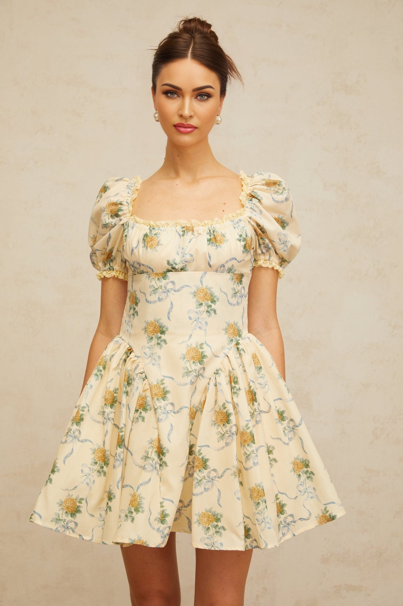 A yellow mini dress with a floral print pattern and shirred fabric detailing called the Tiphaine dress