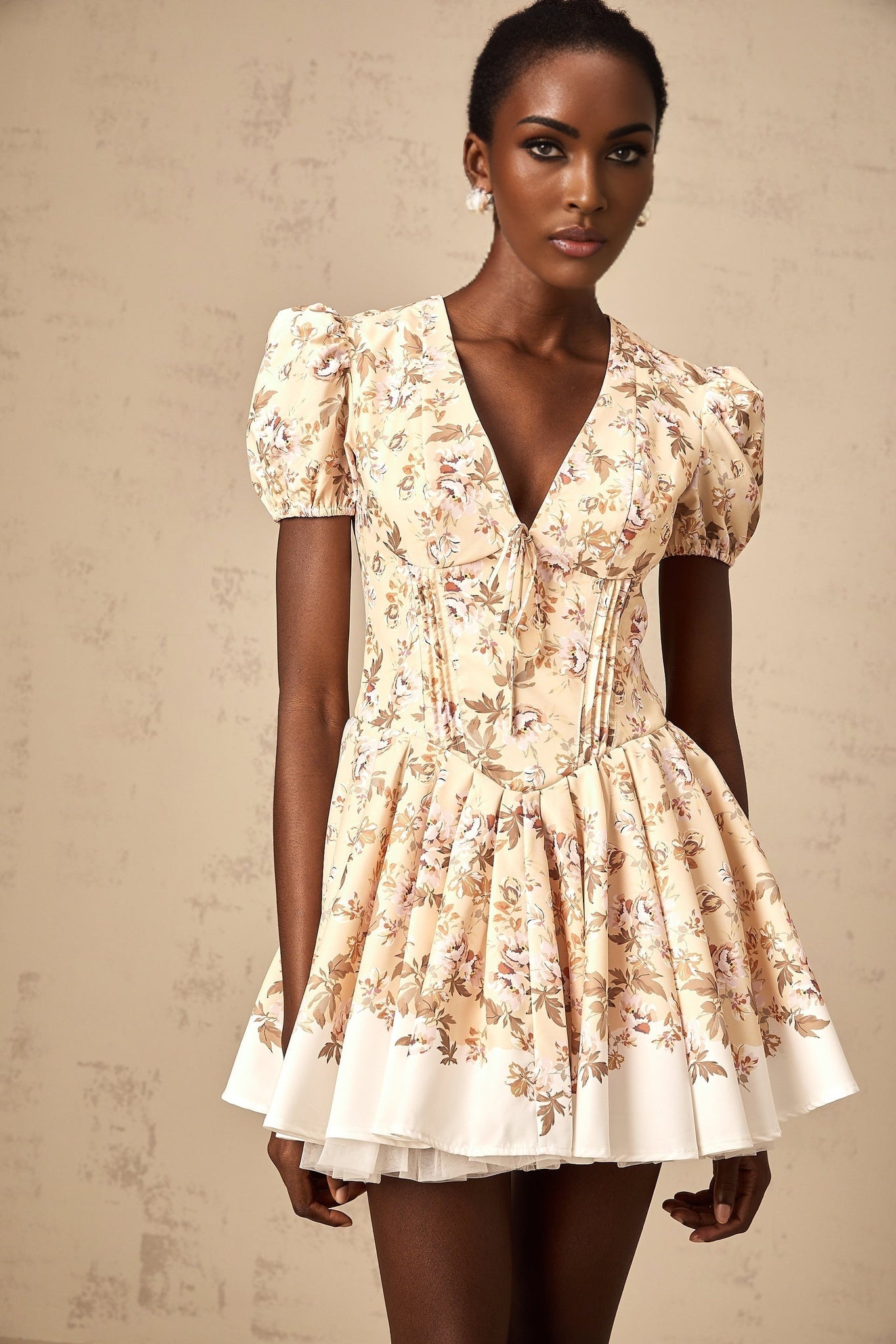 A yellow mini dress with floral print and pleated design featuring short sleeves and a feminine silhouette