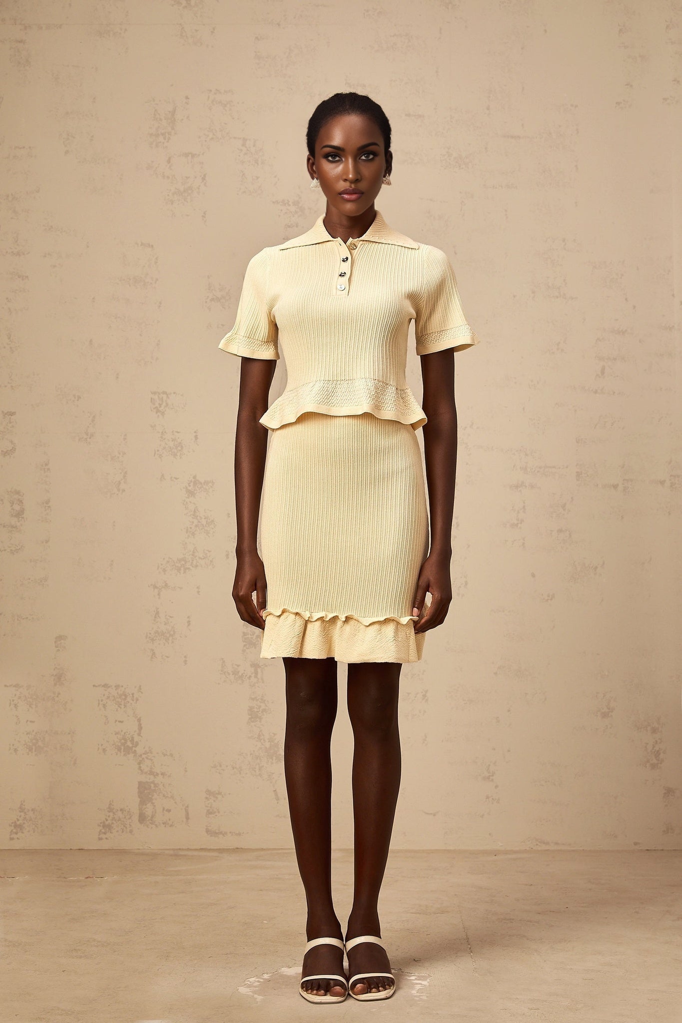 A yellow ribbed knit matching set featuring a ruffled top and skirt The top has short sleeves and the skirt is knee length Both pieces have a textured ribbed pattern and ruffled details for a feminine look