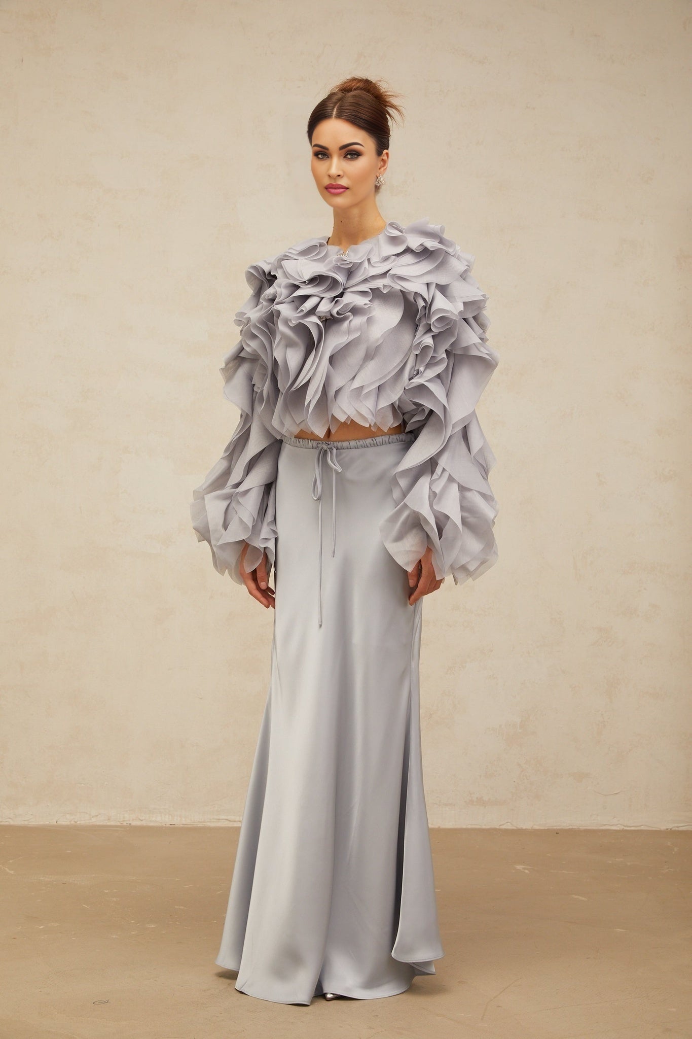 A young girl wearing a light blue blouse with a large bow and ruffles paired with a matching skirt in the same color The outfit has a Zelda inspired design