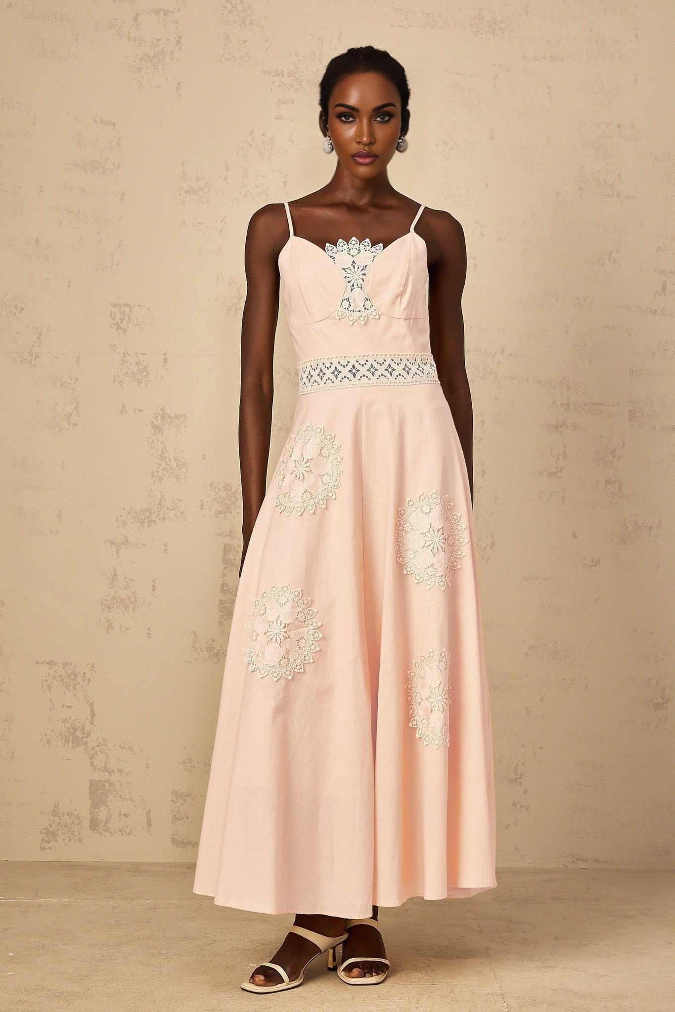A young girl wearing a pink blouse with floral embroidery paired with a matching dress set The outfit features delicate floral patterns and a soft pink color suitable for special occasions