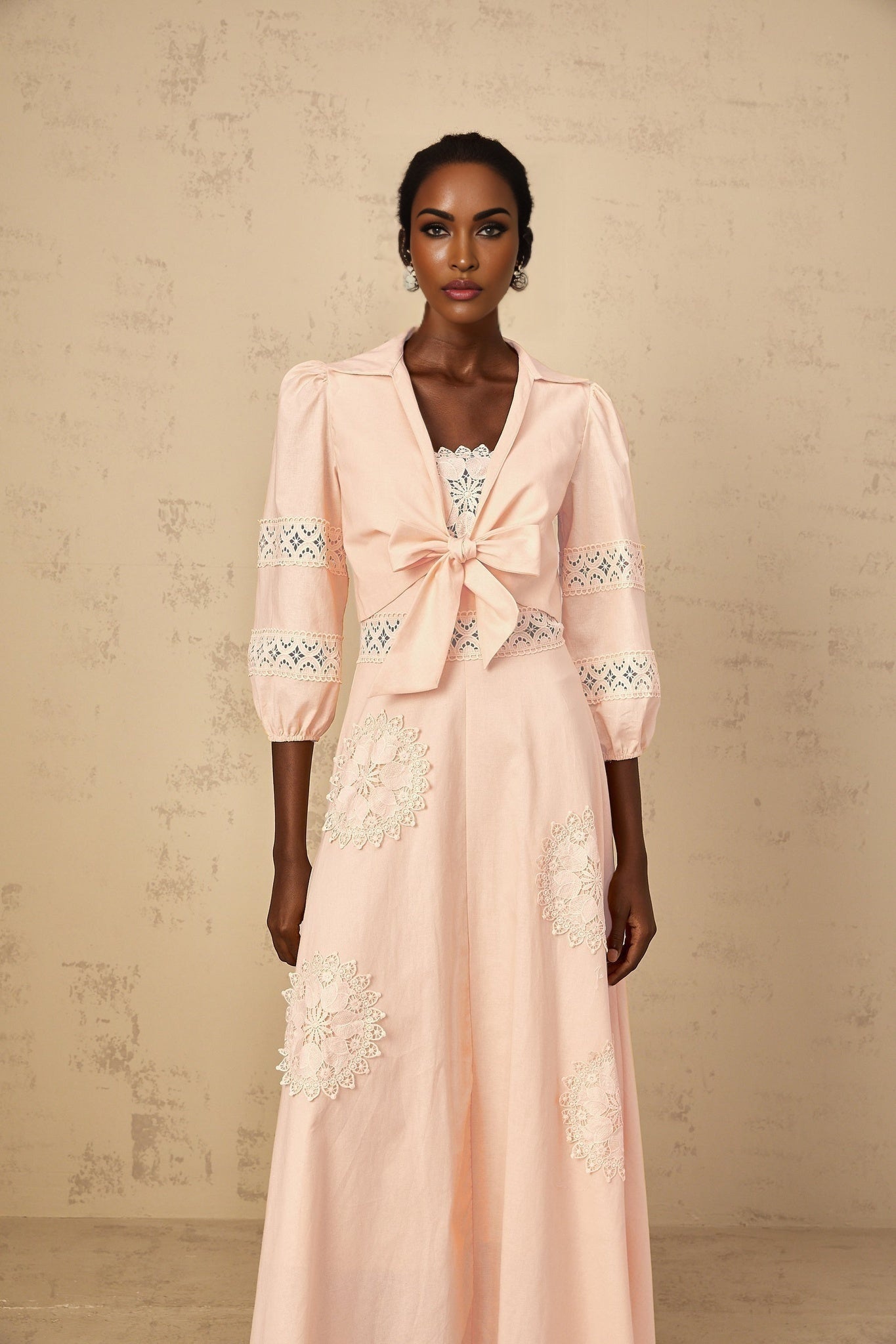 A young girl wearing a pink blouse with floral embroidery paired with a matching dress The set features delicate floral patterns and a feminine design suitable for special occasions