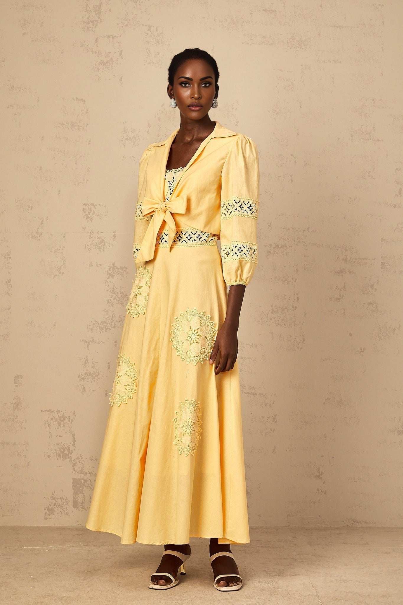 A young girl wearing a yellow floral embroidered blouse paired with a matching dress set featuring delicate floral patterns and designs