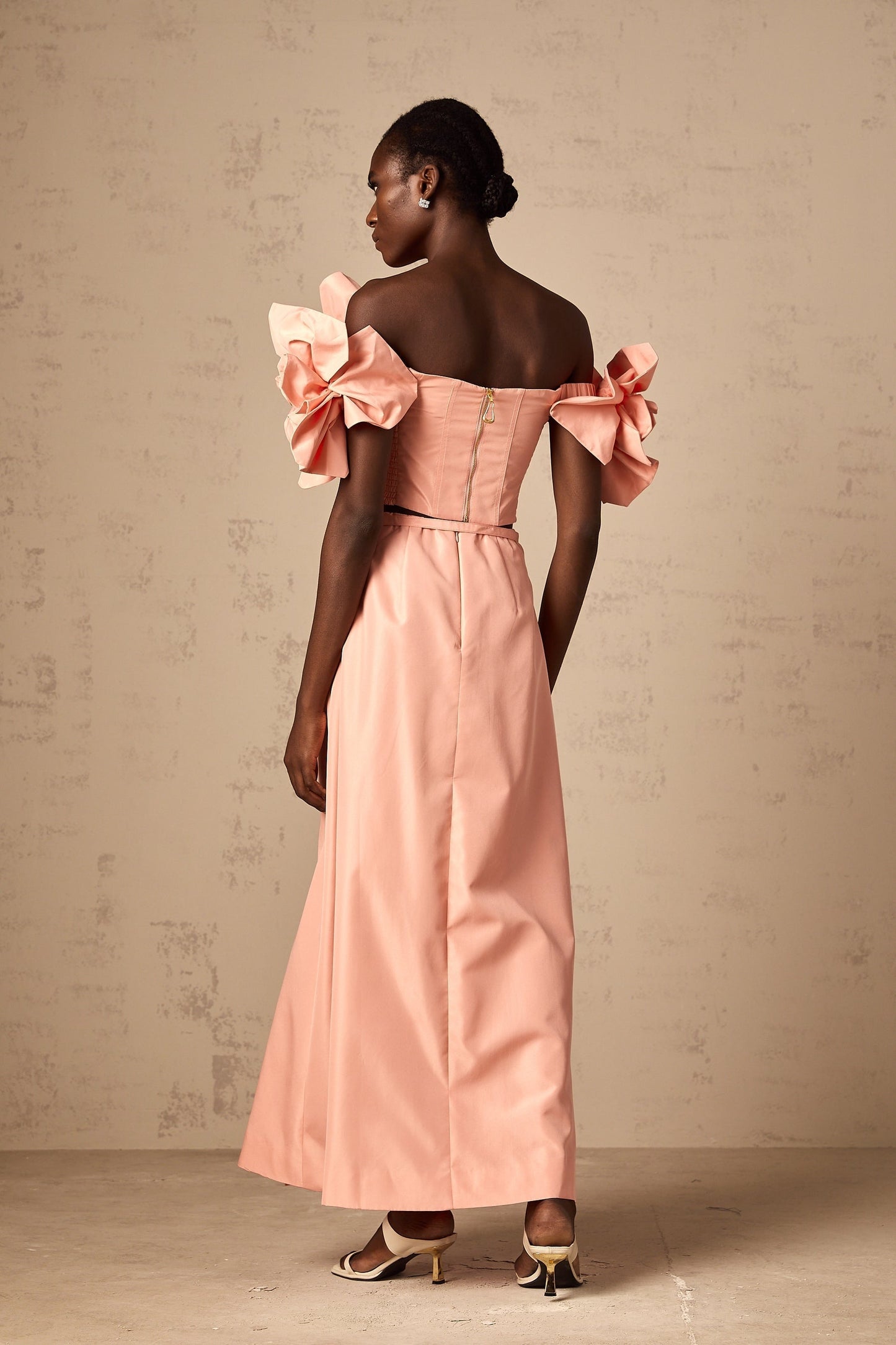 A young woman wearing a pink twopiece outfit consisting of a top and skirt with floral applique details The set has a feminine and romantic design perfect for spring or summer occasions