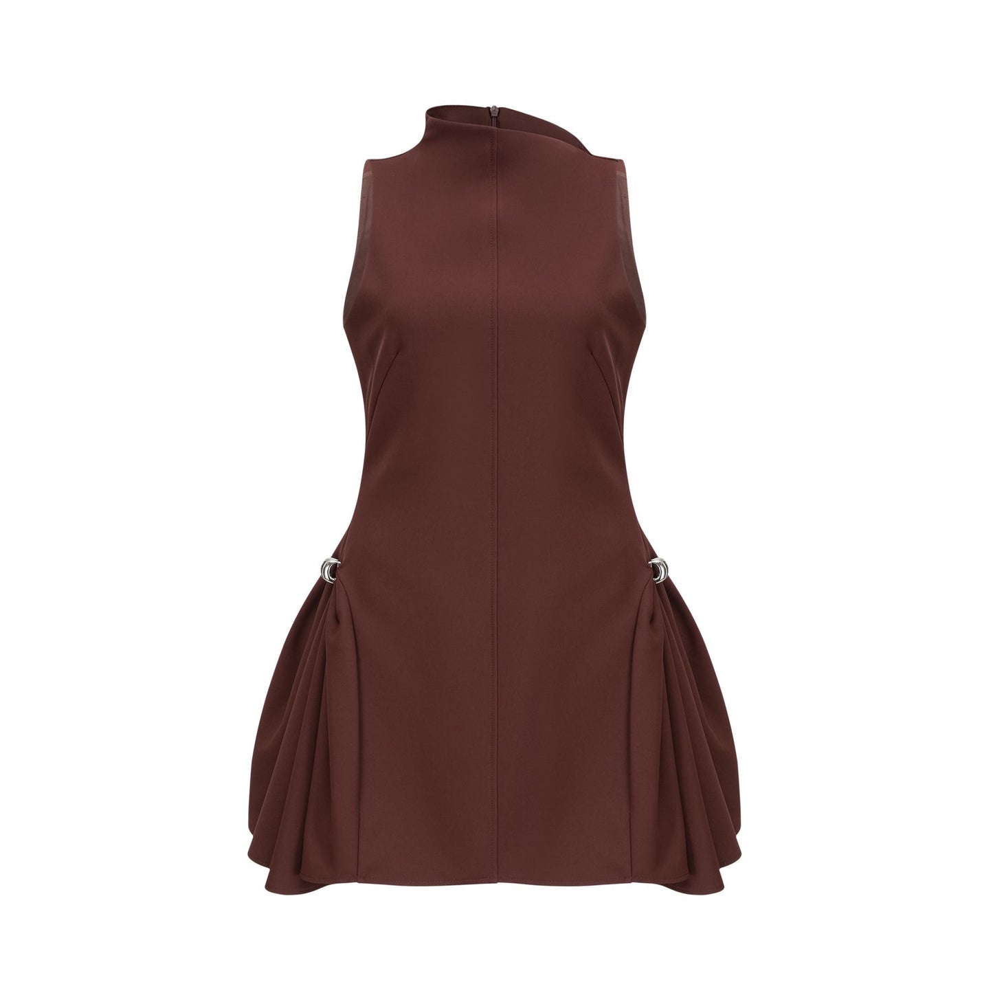 A young woman wearing a short brown dress with an asymmetric neckline and puffed sleeves standing against a plain background