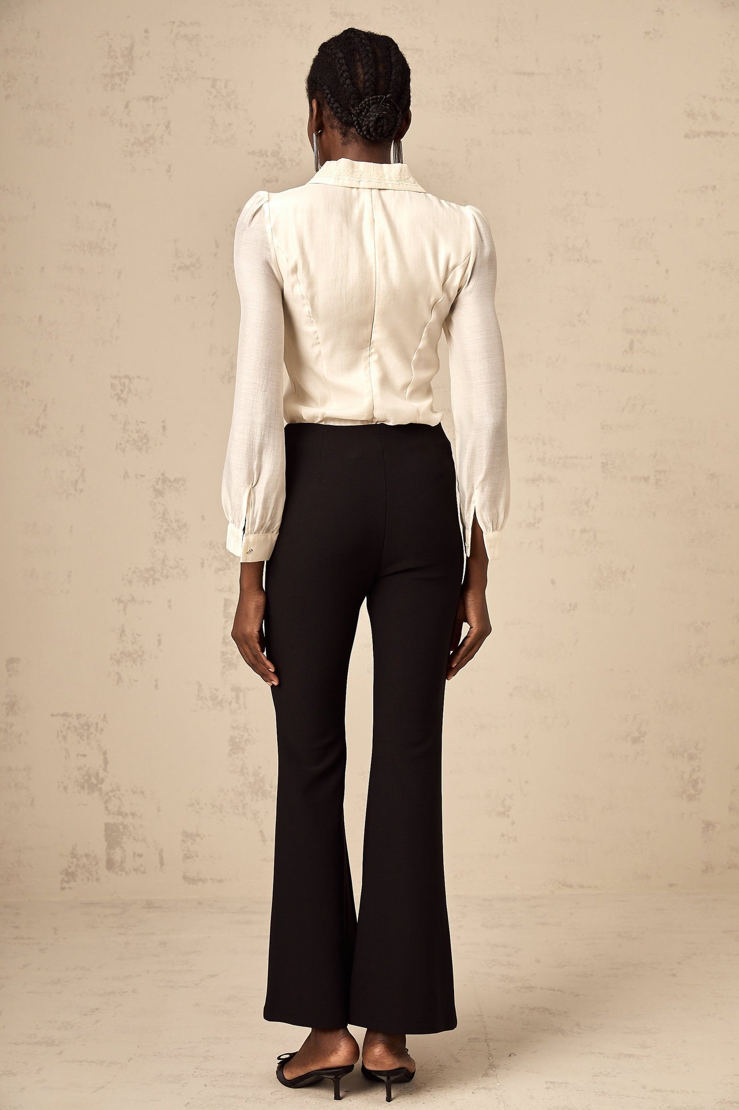 Black flared trousers with decorative bow detail at waist