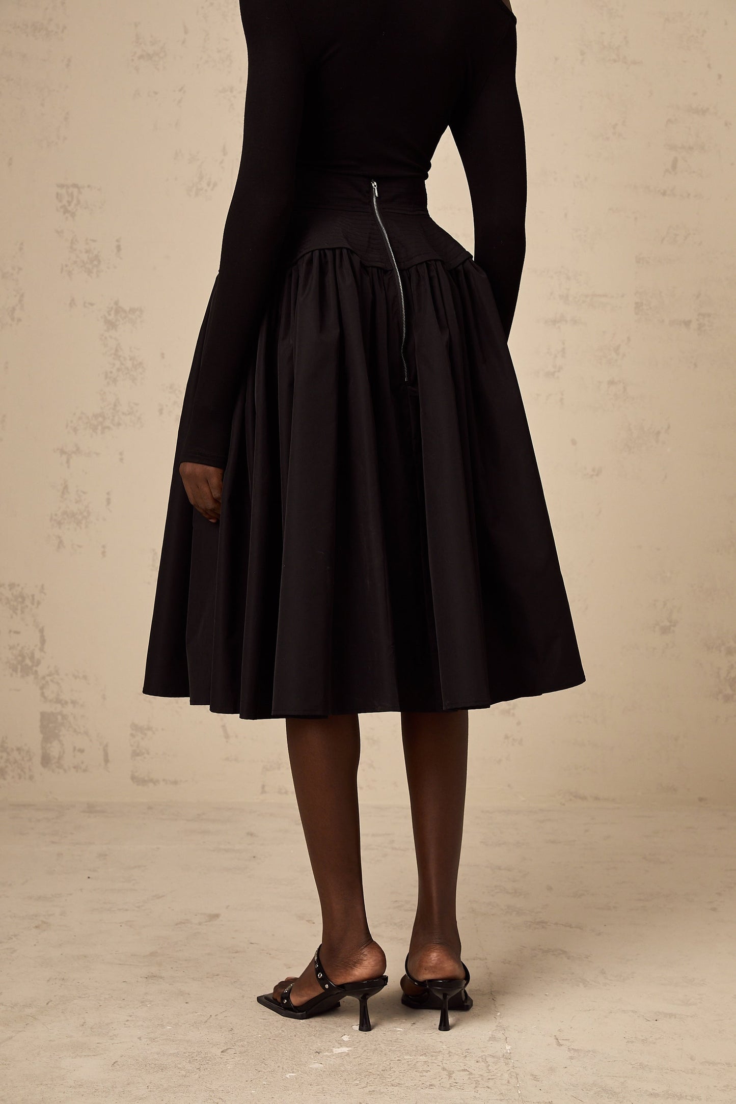 Black pleated midi skirt with flared silhouette named Pauline