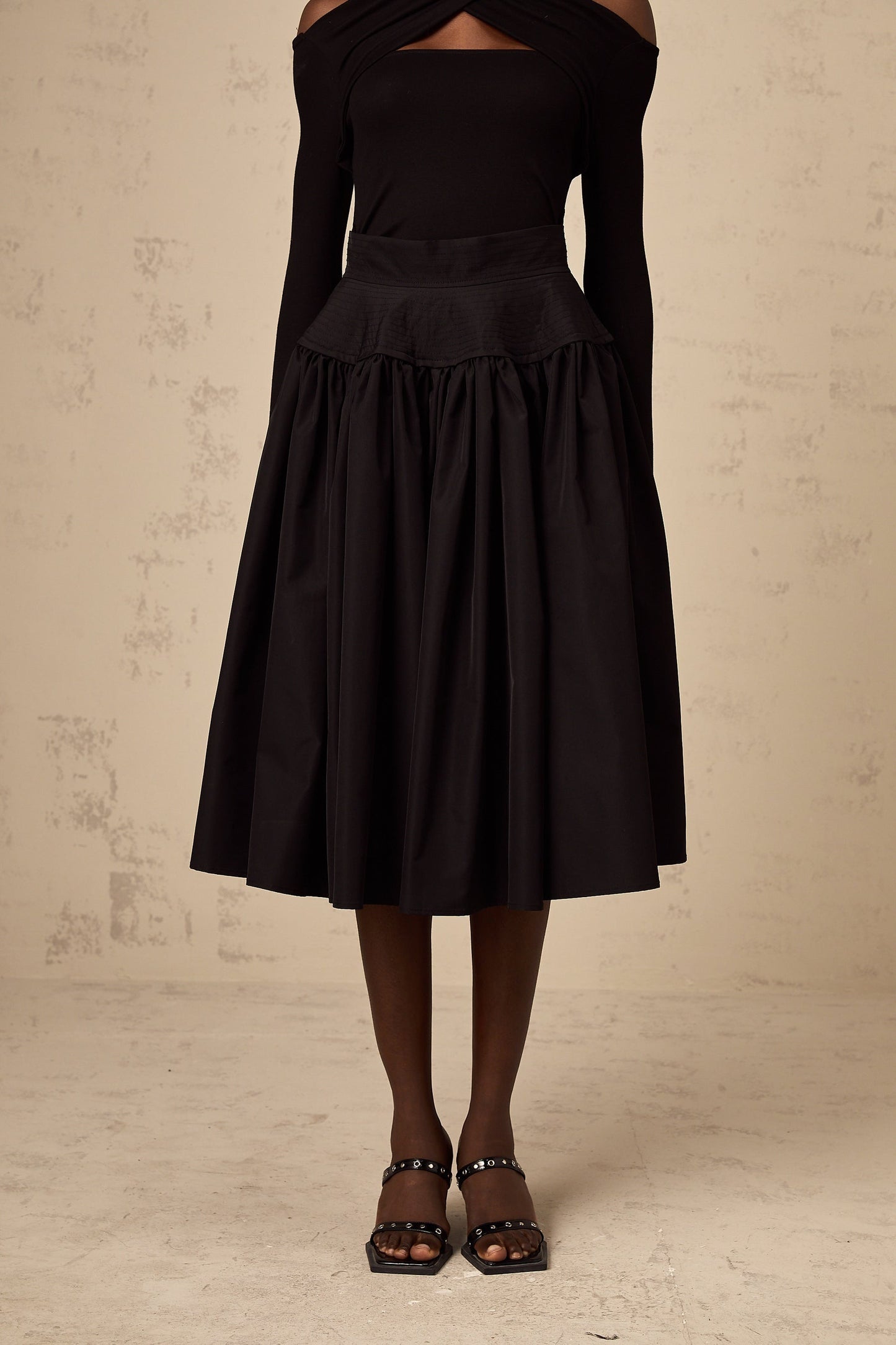 Black pleated midi skirt with flared silhouette named Pauline