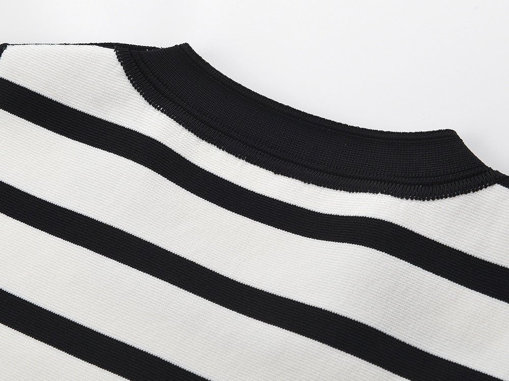 Black and white striped sleeveless body-con dress with gold button accents on shoulders
