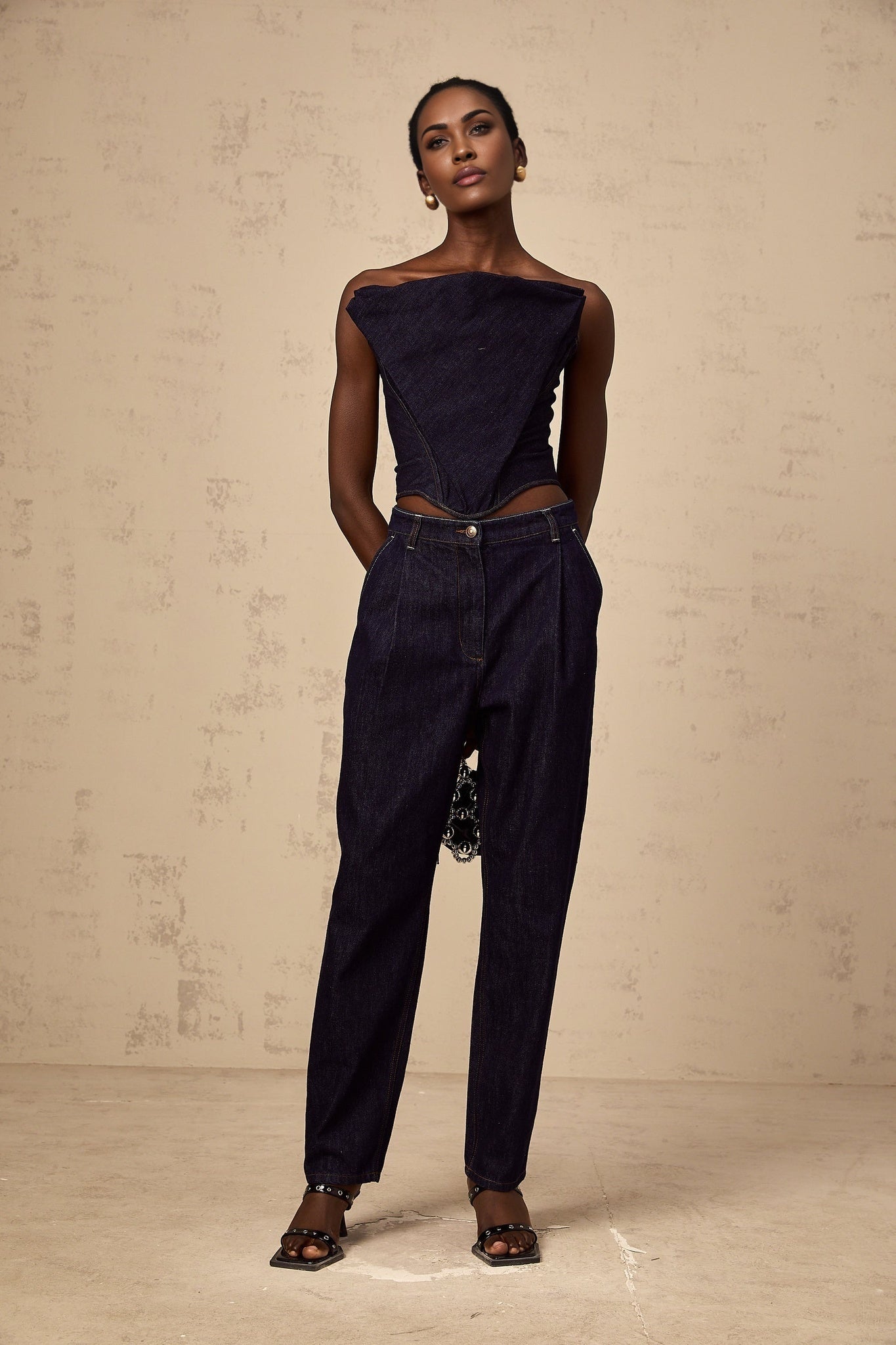 Blue high rise jeans with pleated details on a white background
