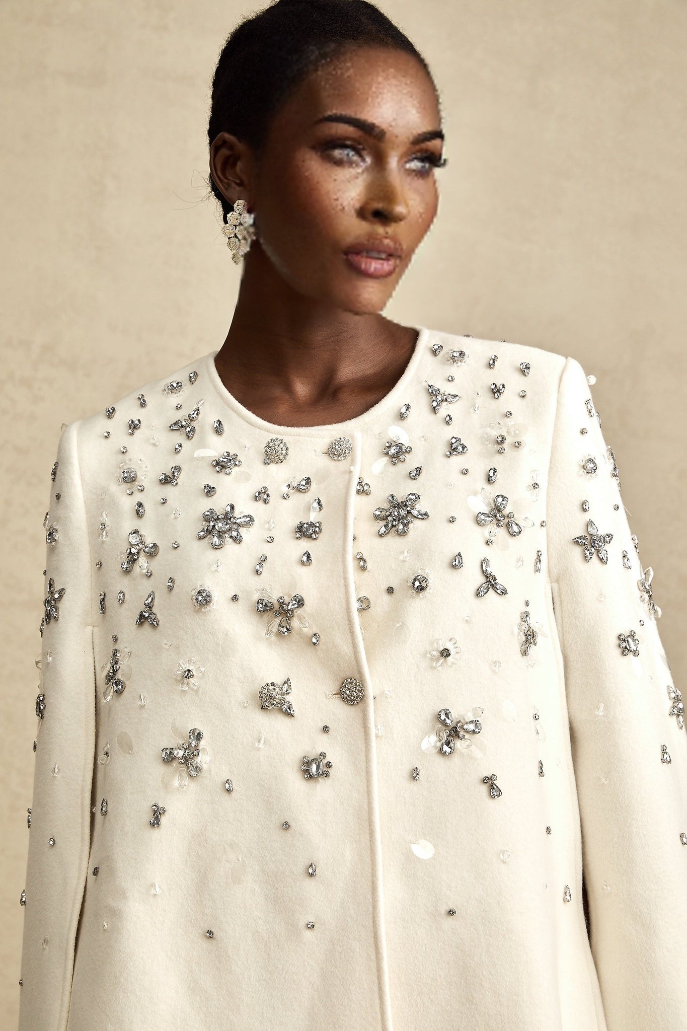 Elegant white jacket with cape design and ornate embellishments on shoulders and sleeves