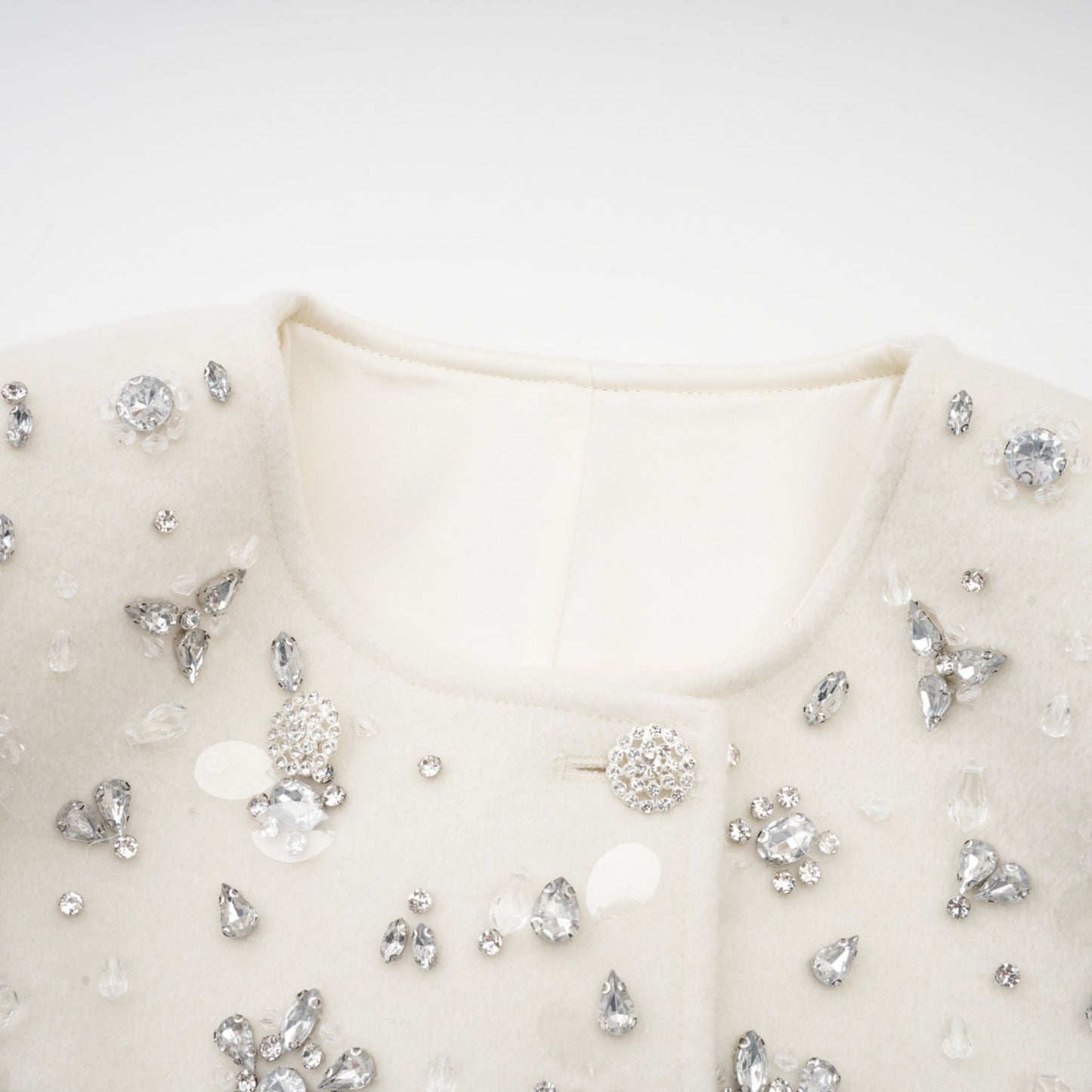 Elegant white jacket with cape design featuring intricate embellishments and beaded details on shoulders and front