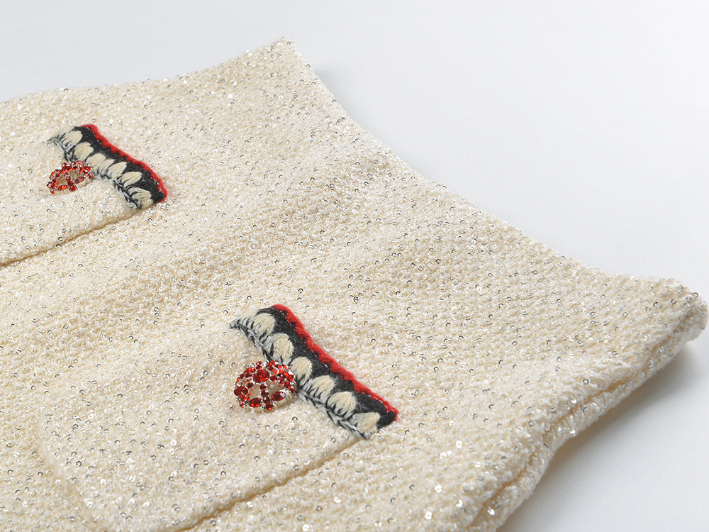 Elegant cream tweed jacket with red and black embroidery, decorative buttons, and a tailored fit