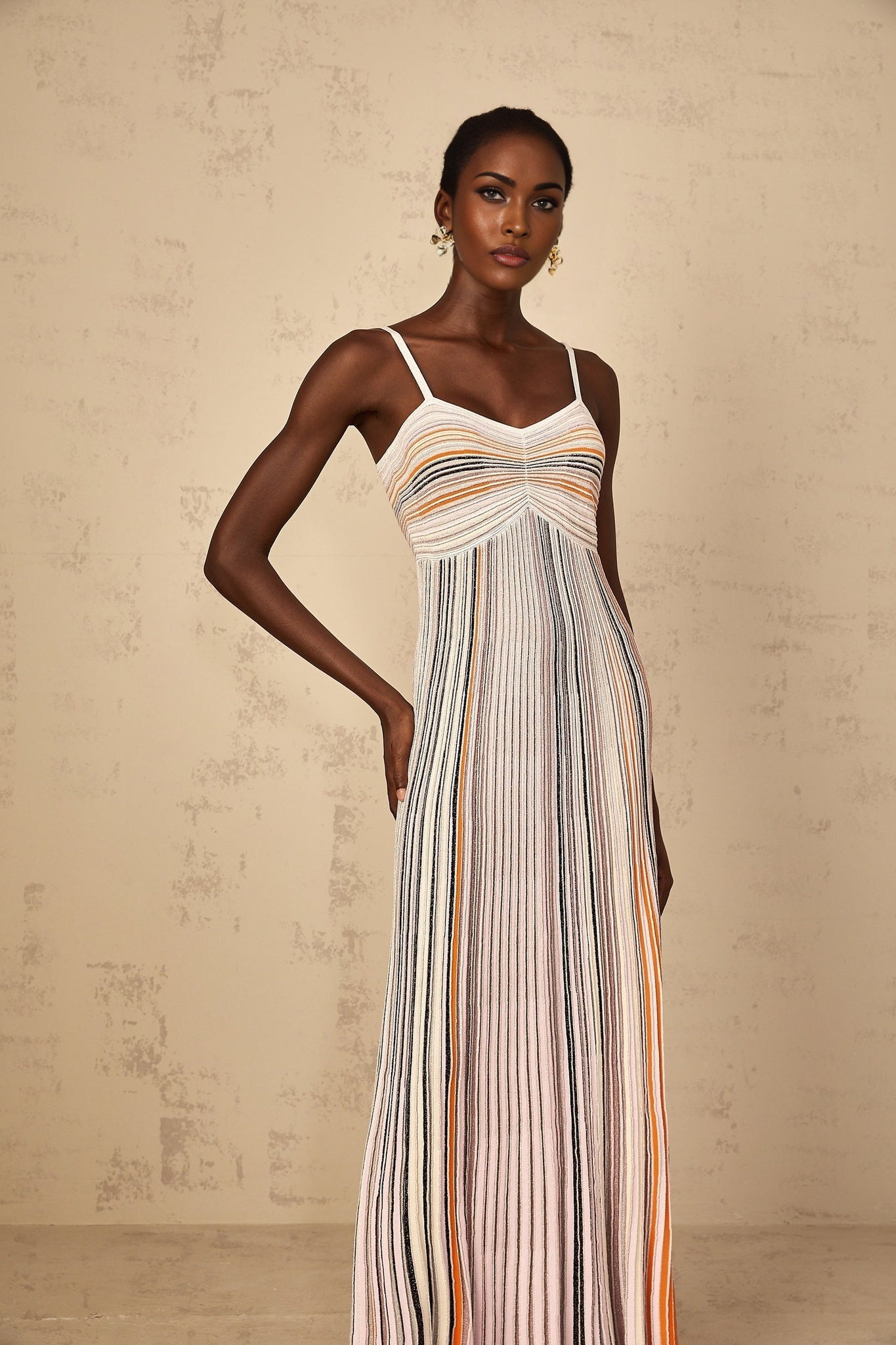 Neutral toned maxi dress with sequin stripes and knit fabric on a female model
