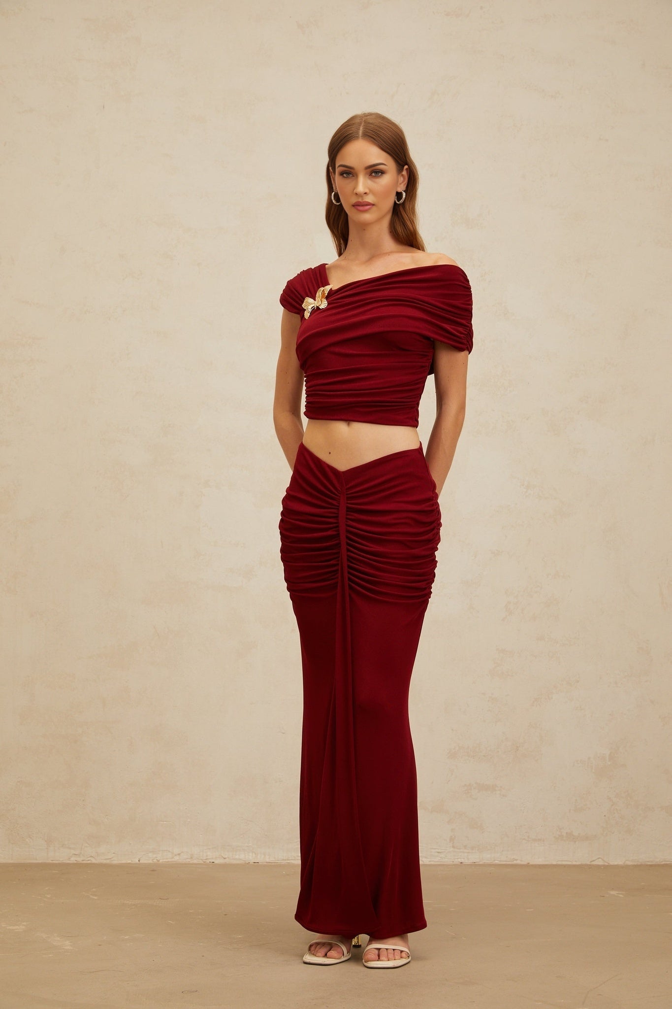Red asymmetrical cropped top and mermaid hem maxi skirt set with butterfly brooch and ruched detailing