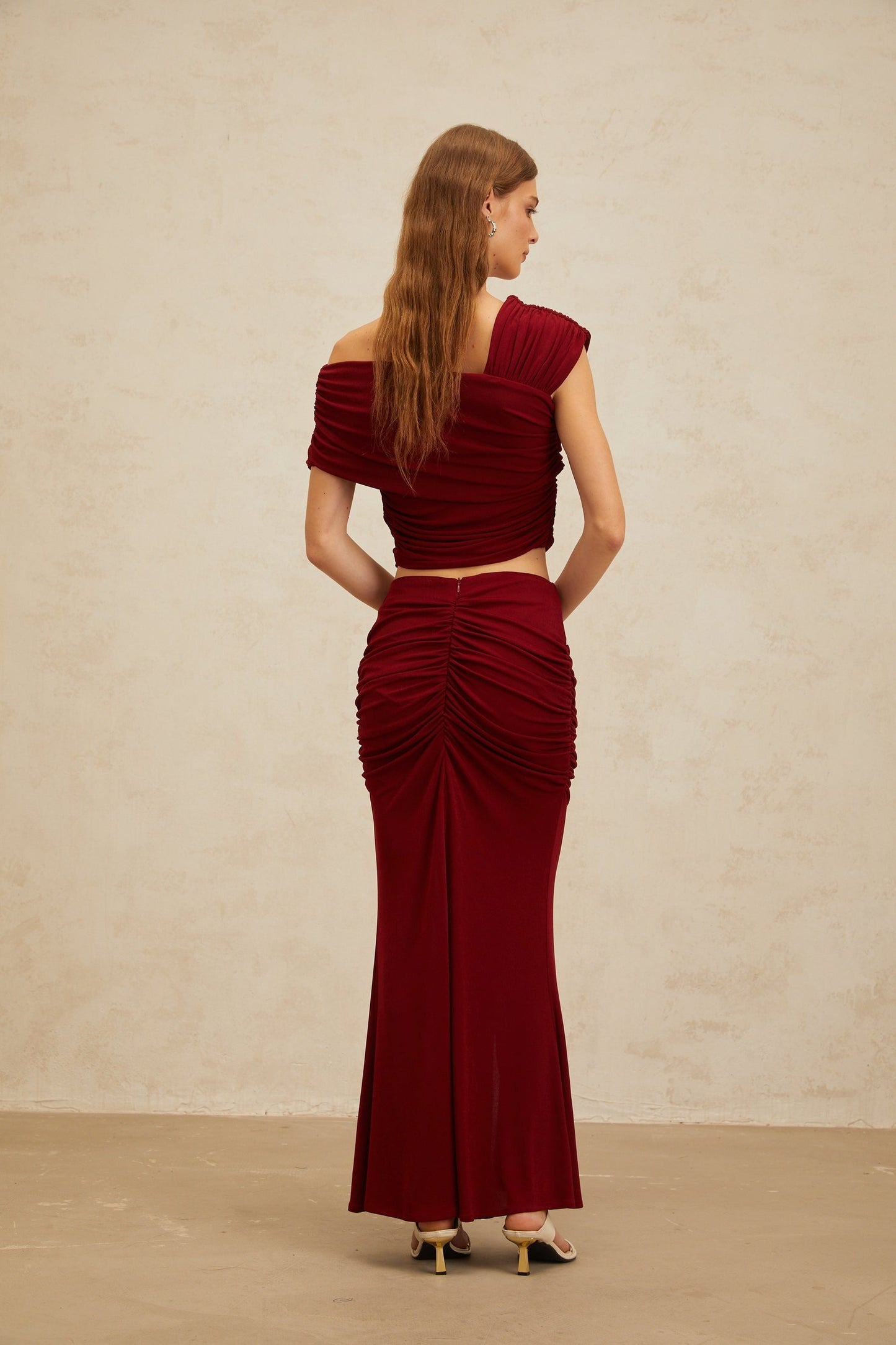 Red asymmetrical cropped top with butterfly brooch and cap sleeves, paired with red ruched mermaid hem maxi skirt