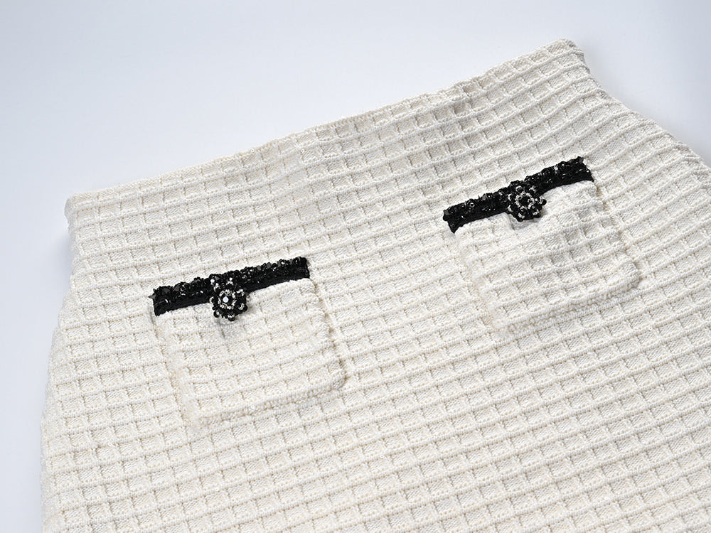 Textured white knitted jacket with black trim and decorative buttons paired with a ruffled hem skirt