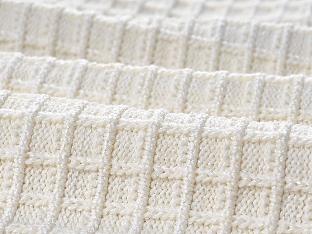 Textured white knitted jacket with black trim and decorative buttons paired with a ruffled hem skirt
