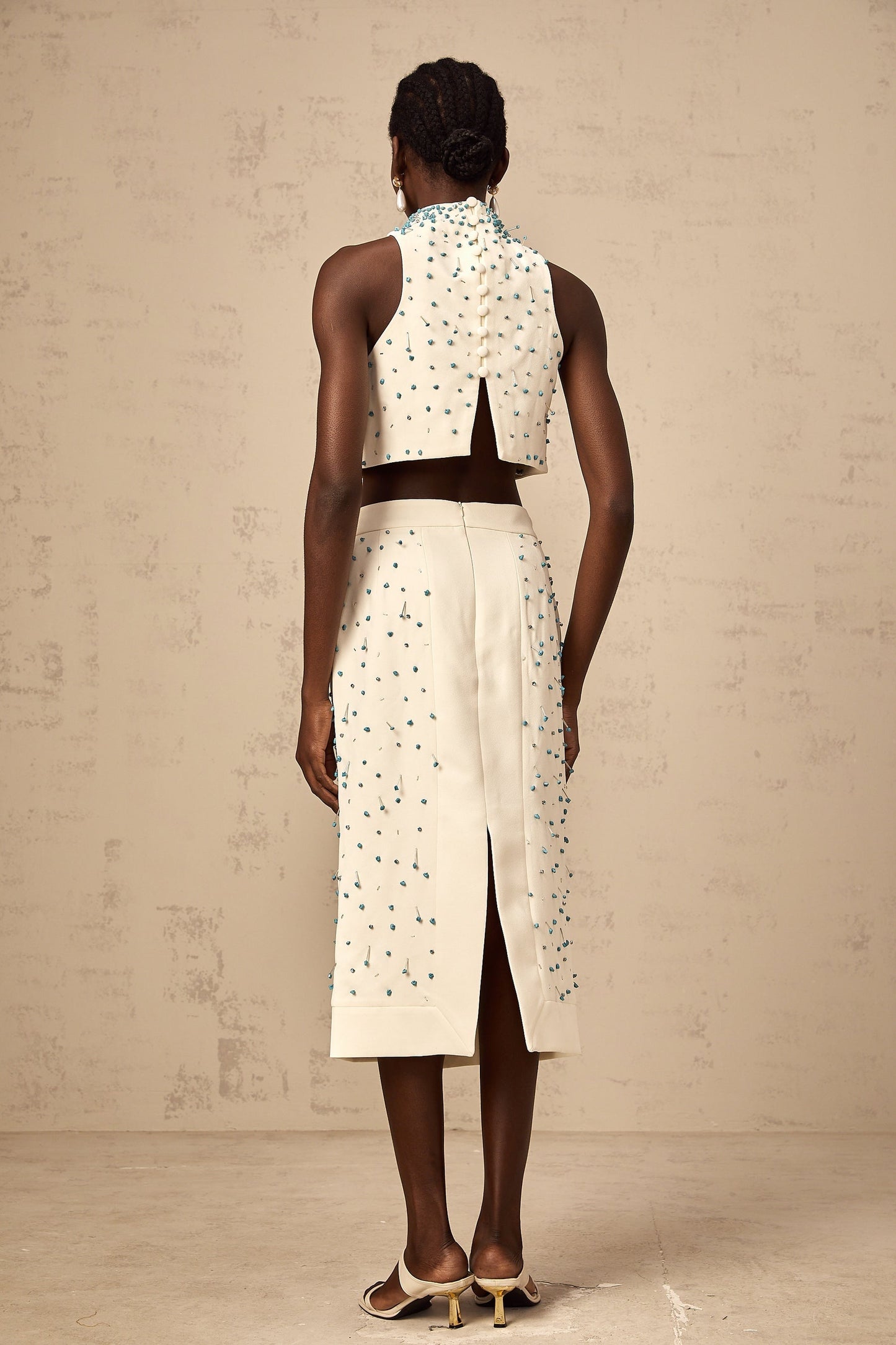 Two piece off white outfit with embellishments consisting of a top and skirt