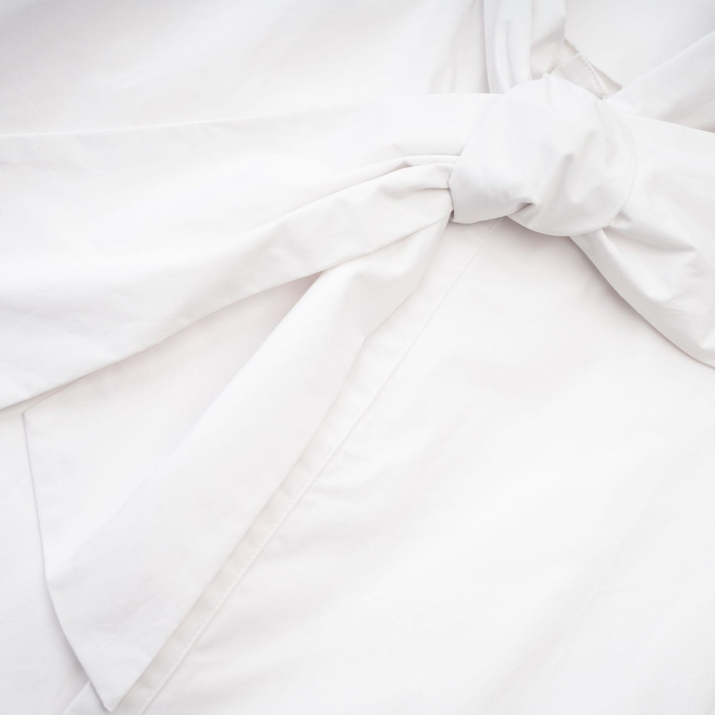 White cotton buttonup shirt with tie front detail and long sleeves