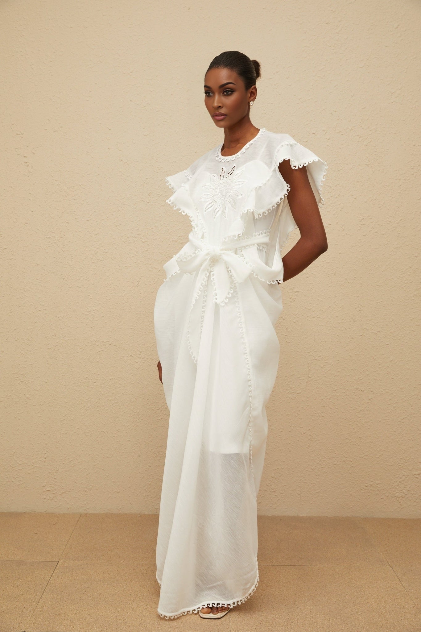 White cotton maxi dress with floral embroidery, cap sleeves, and tied waist