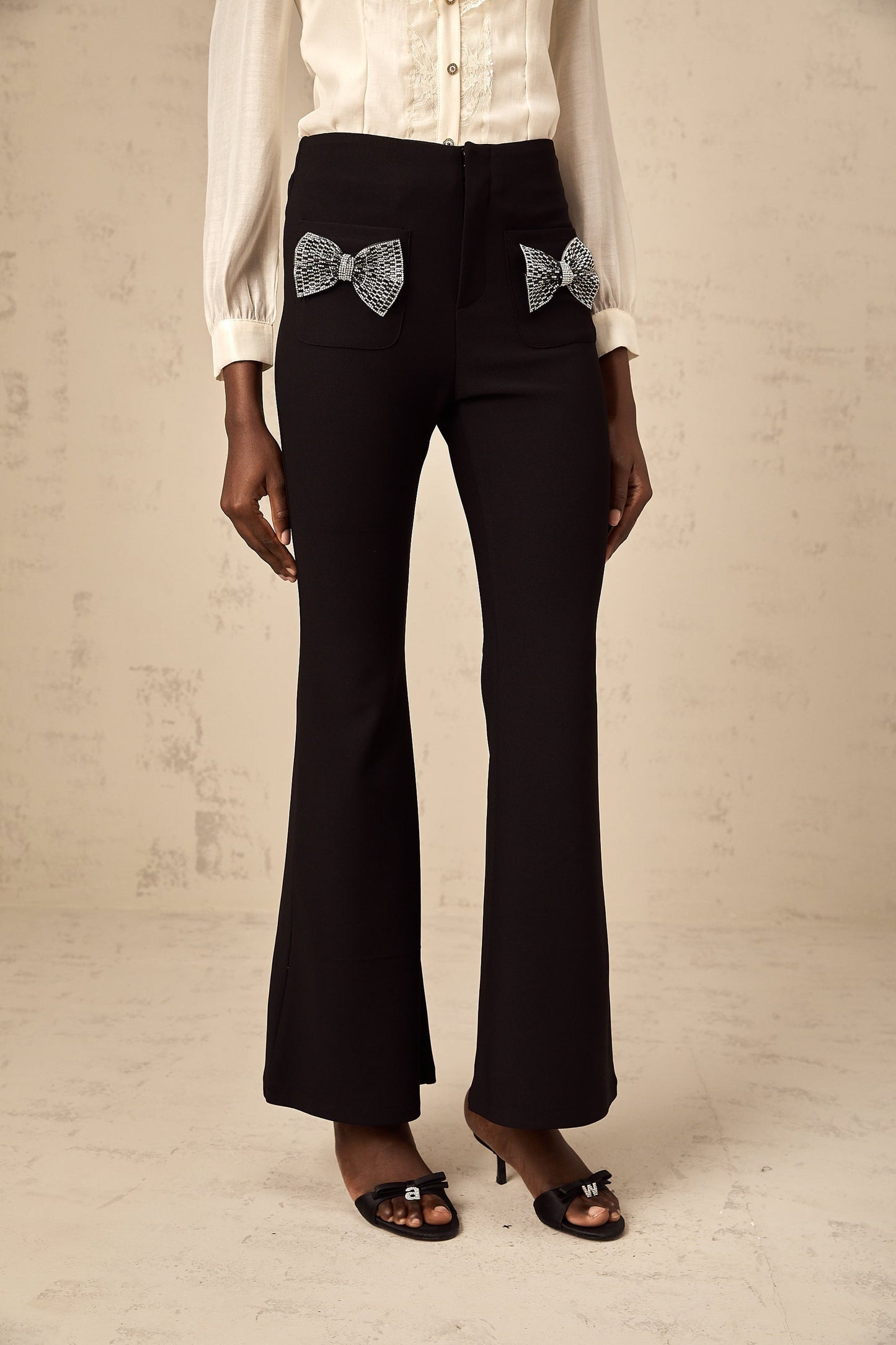 White flared trousers with decorative bow detail at waist