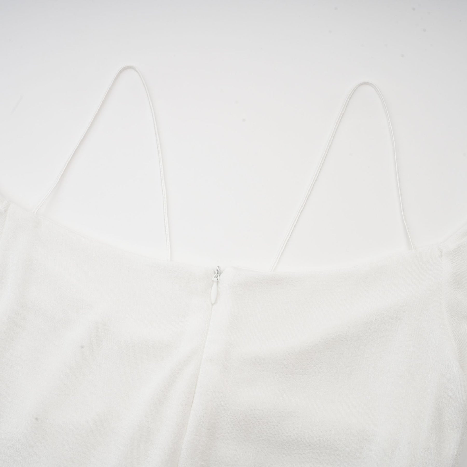 White offshoulder maxi dress with panelled design worn by a model standing against a plain background