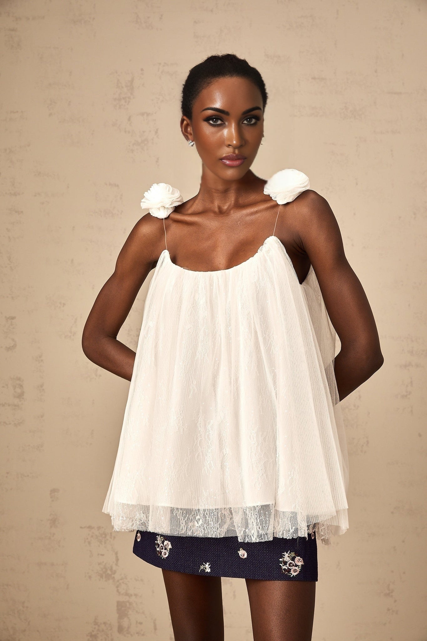 White sleeveless top with sheer mesh fabric and floral appliques