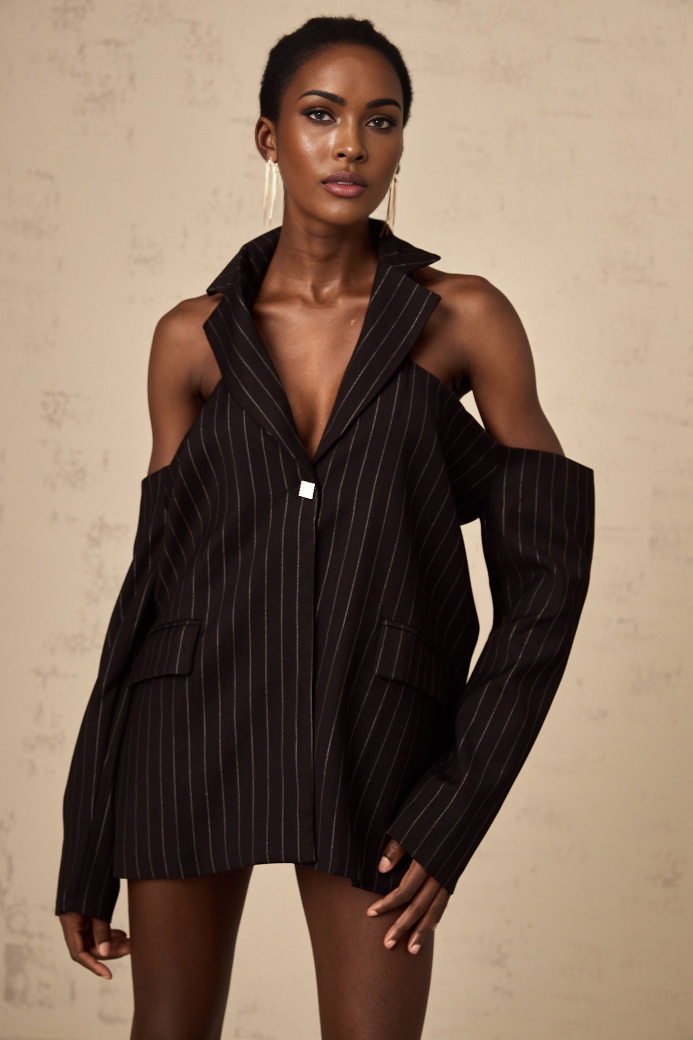 Woman wearing a black blazer with white stripes and an open back design
