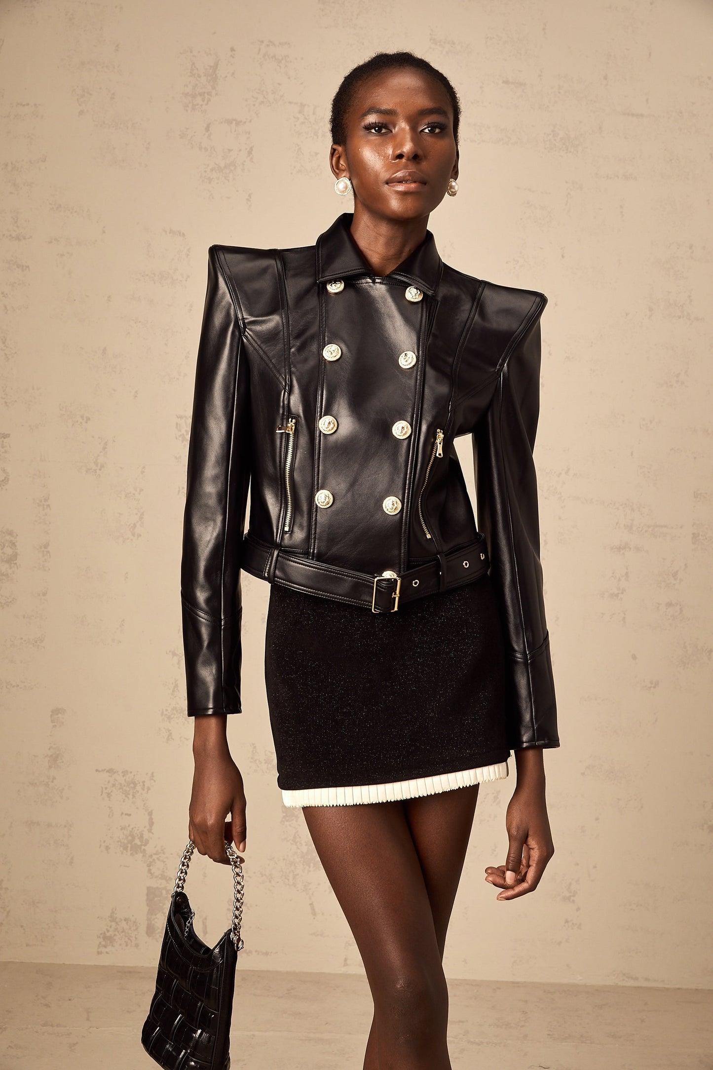 Woman wearing a black faux leather jacket with double breasted front closure and lapel collar