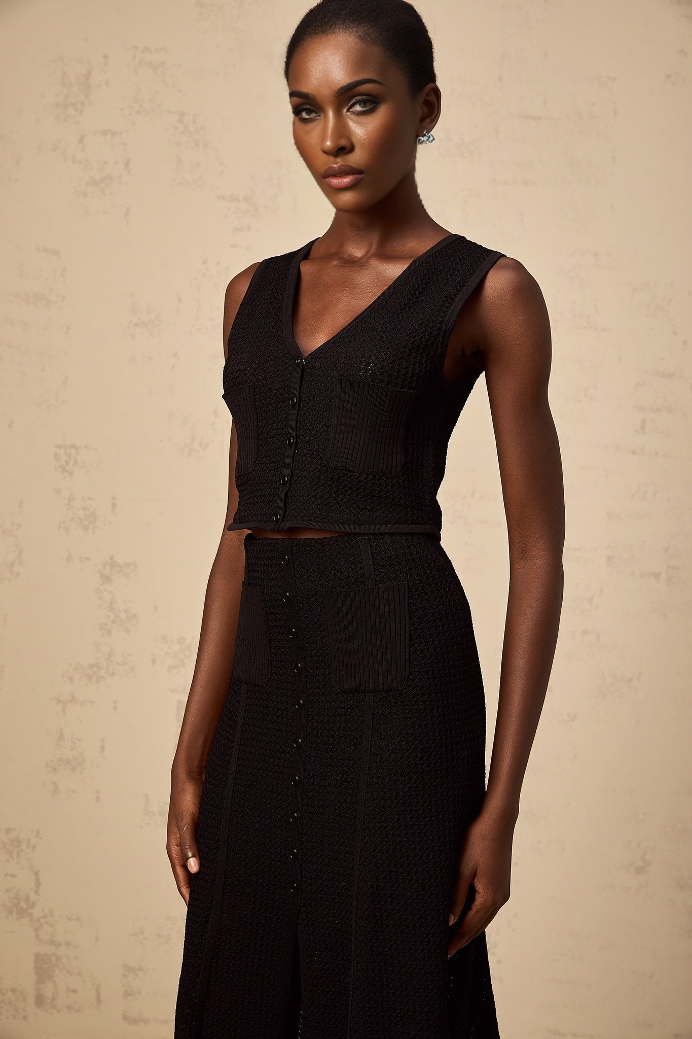 Woman wearing a black matching set consisting of a pointelle knit top and skirt called Babette