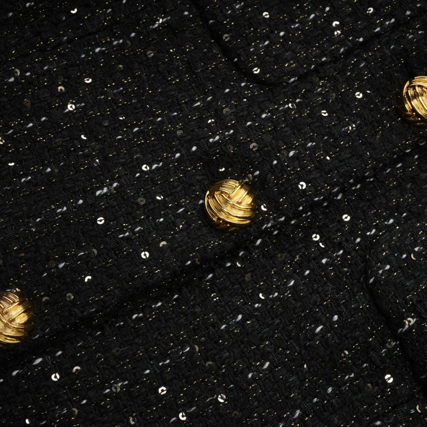 Woman wearing a black mini dress with sequin panels and tweed fabric featuring a sleeveless design and fitted silhouette