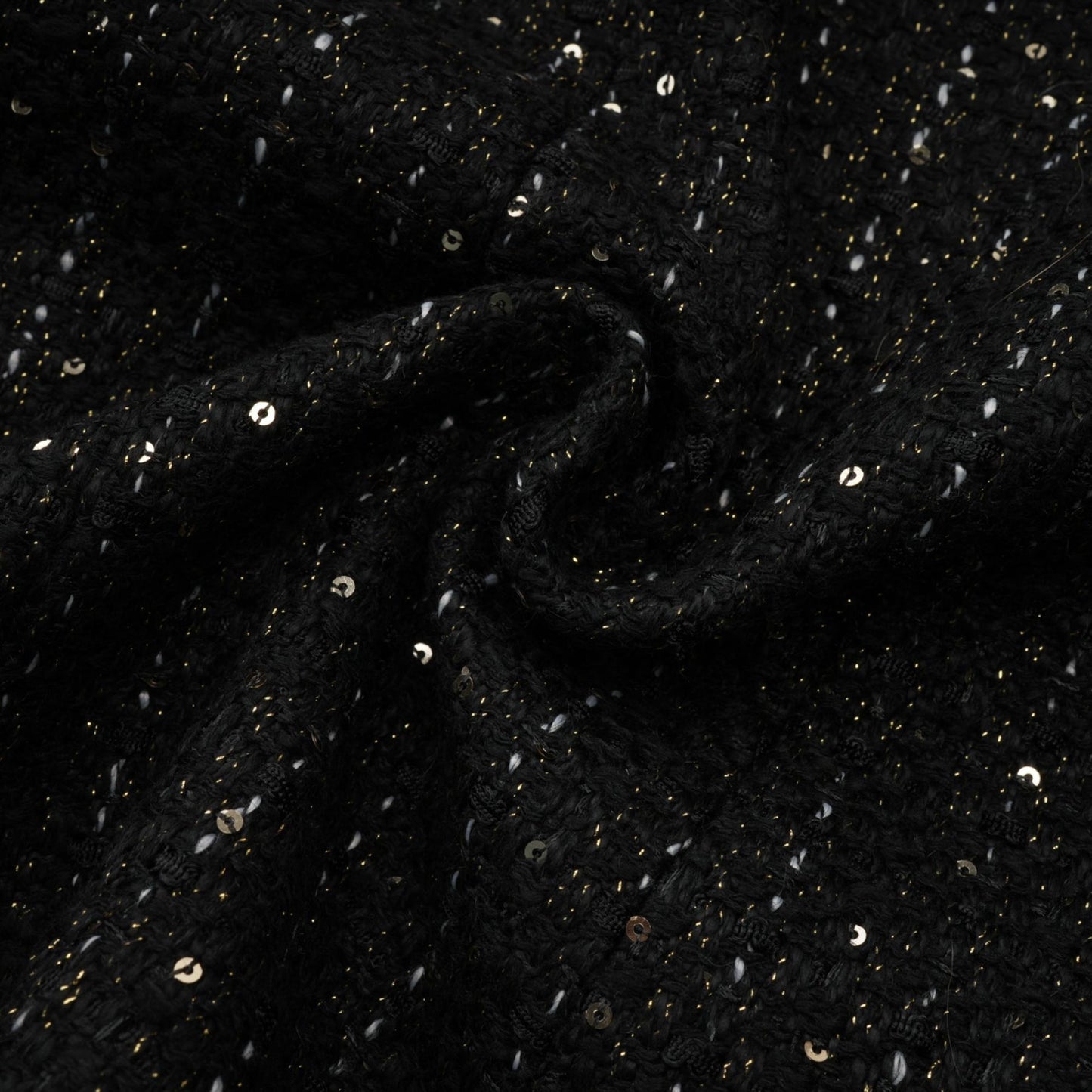 Woman wearing a black mini dress with tweed fabric and sequin panels standing in a neutral background