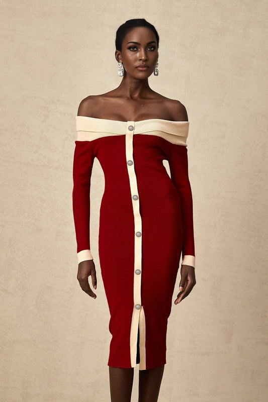 Woman wearing a black offshoulder knit midi dress with a fitted silhouette standing against a plain background