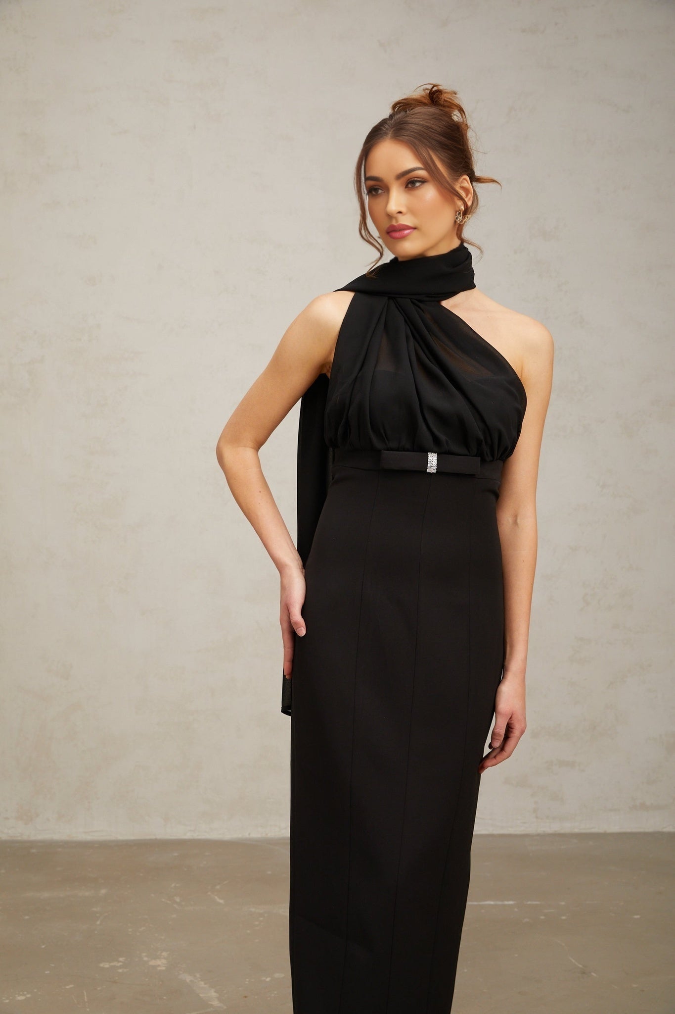 Woman wearing a black one shoulder midi dress with draped fabric details
