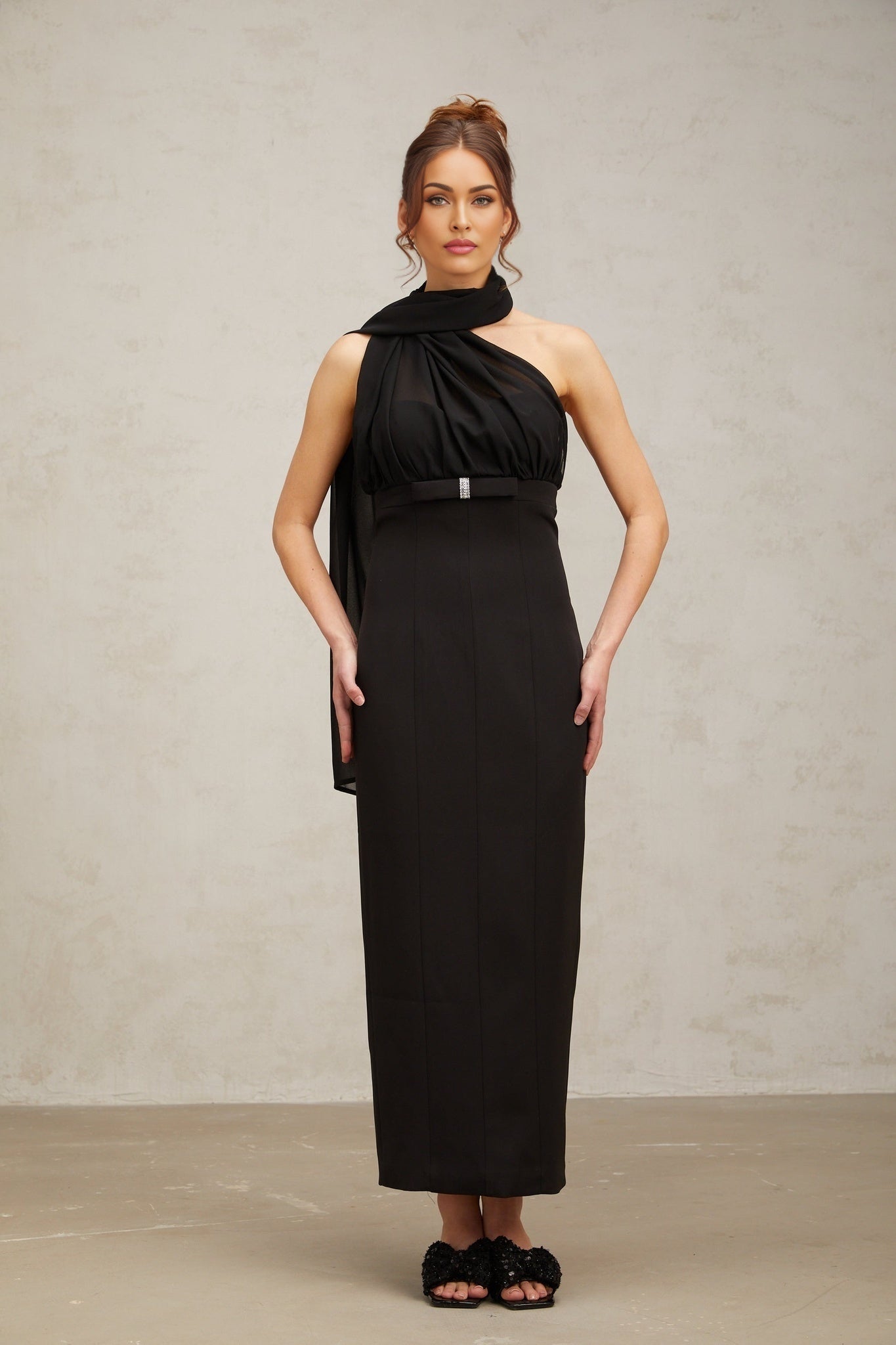 Woman wearing a black oneshoulder midi dress with draped detail