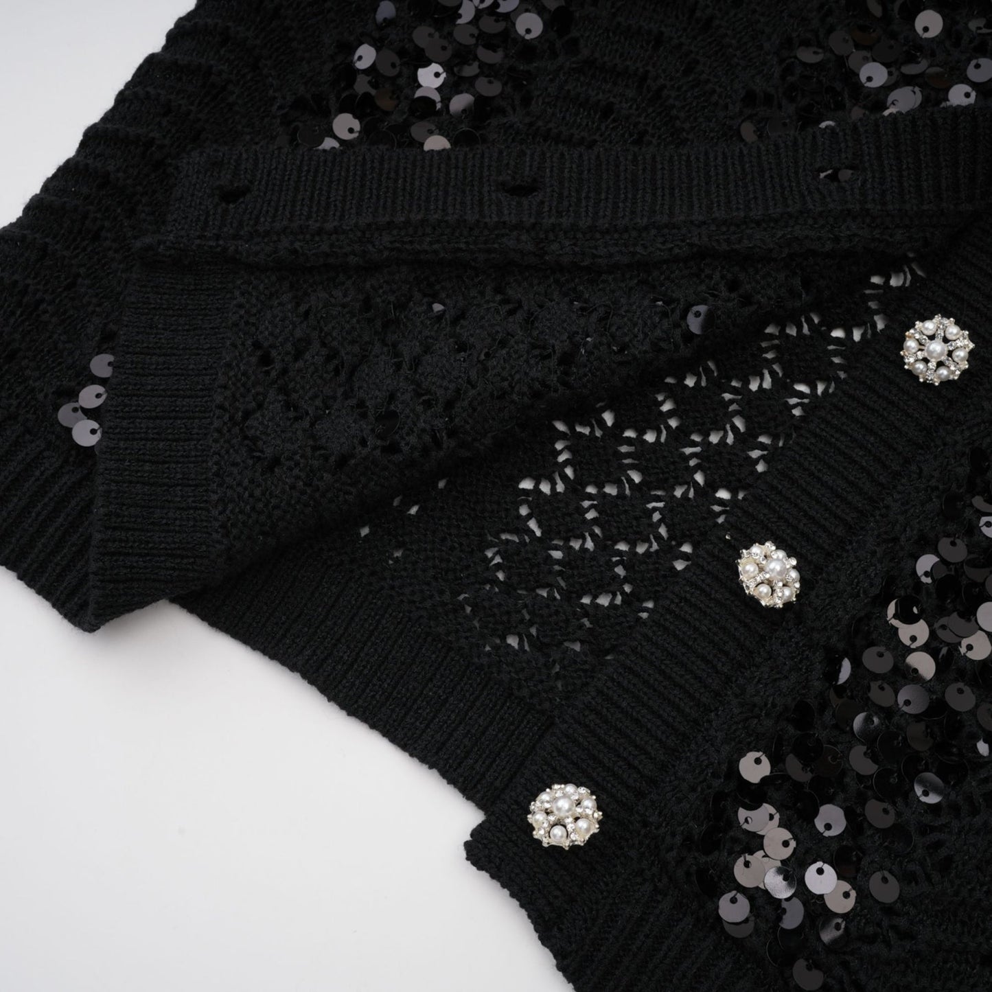 Woman wearing a black sequined matching set with crochet knit cardigan and skirt