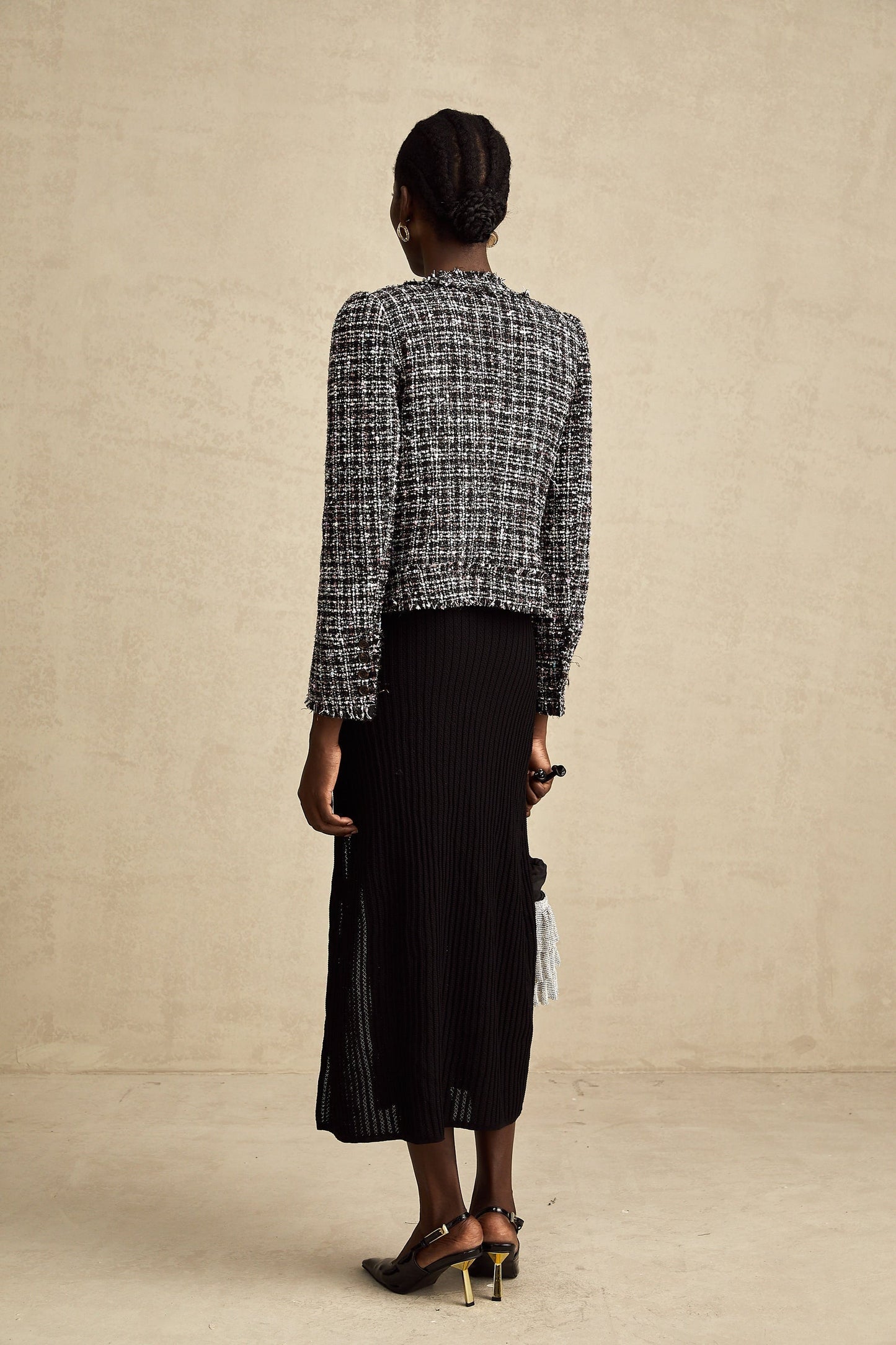 Woman wearing a black tweed jacket with frayed edges and a checked pattern