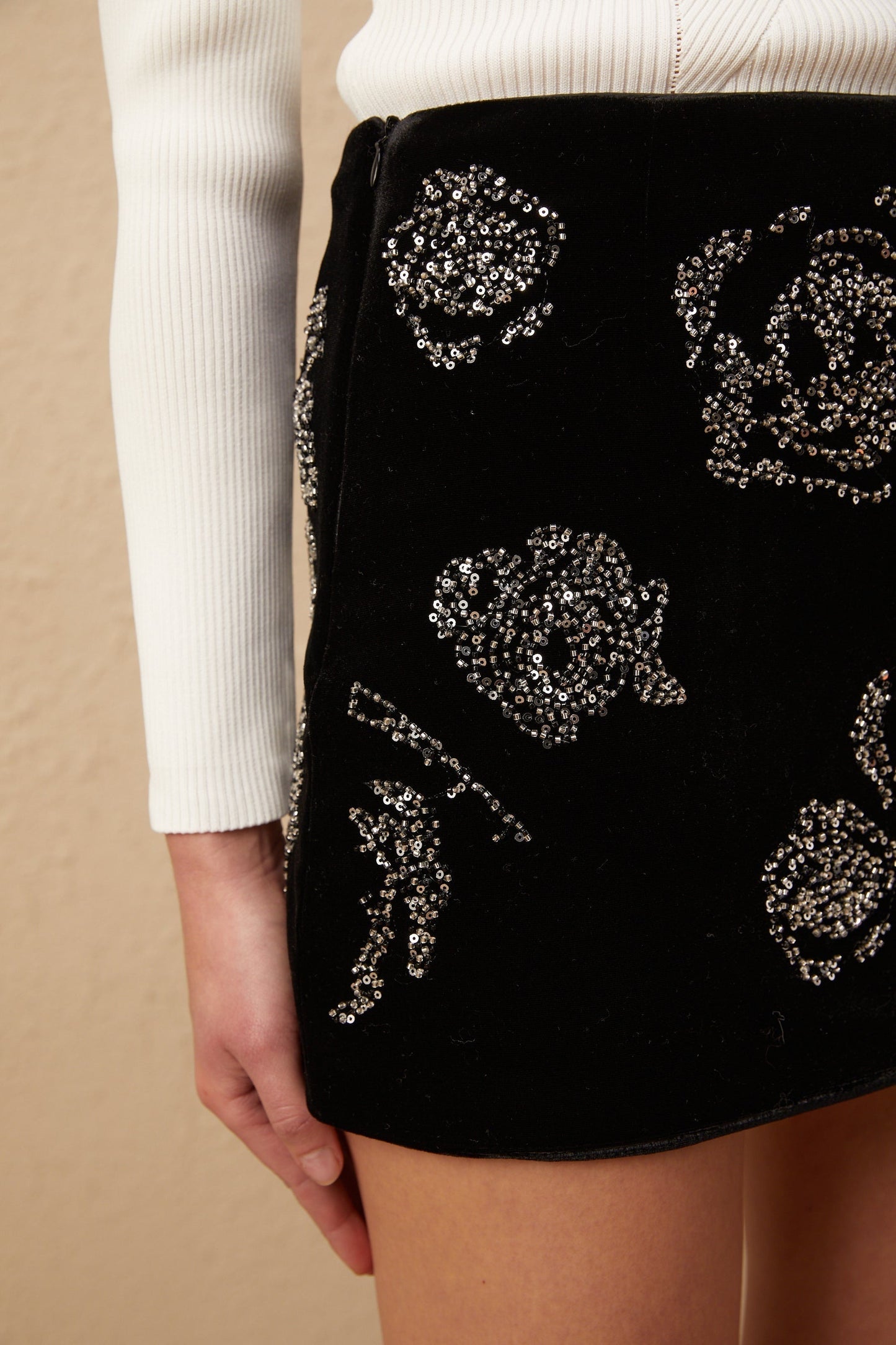 Woman wearing a black velvet mini skirt adorned with shimmering sequins